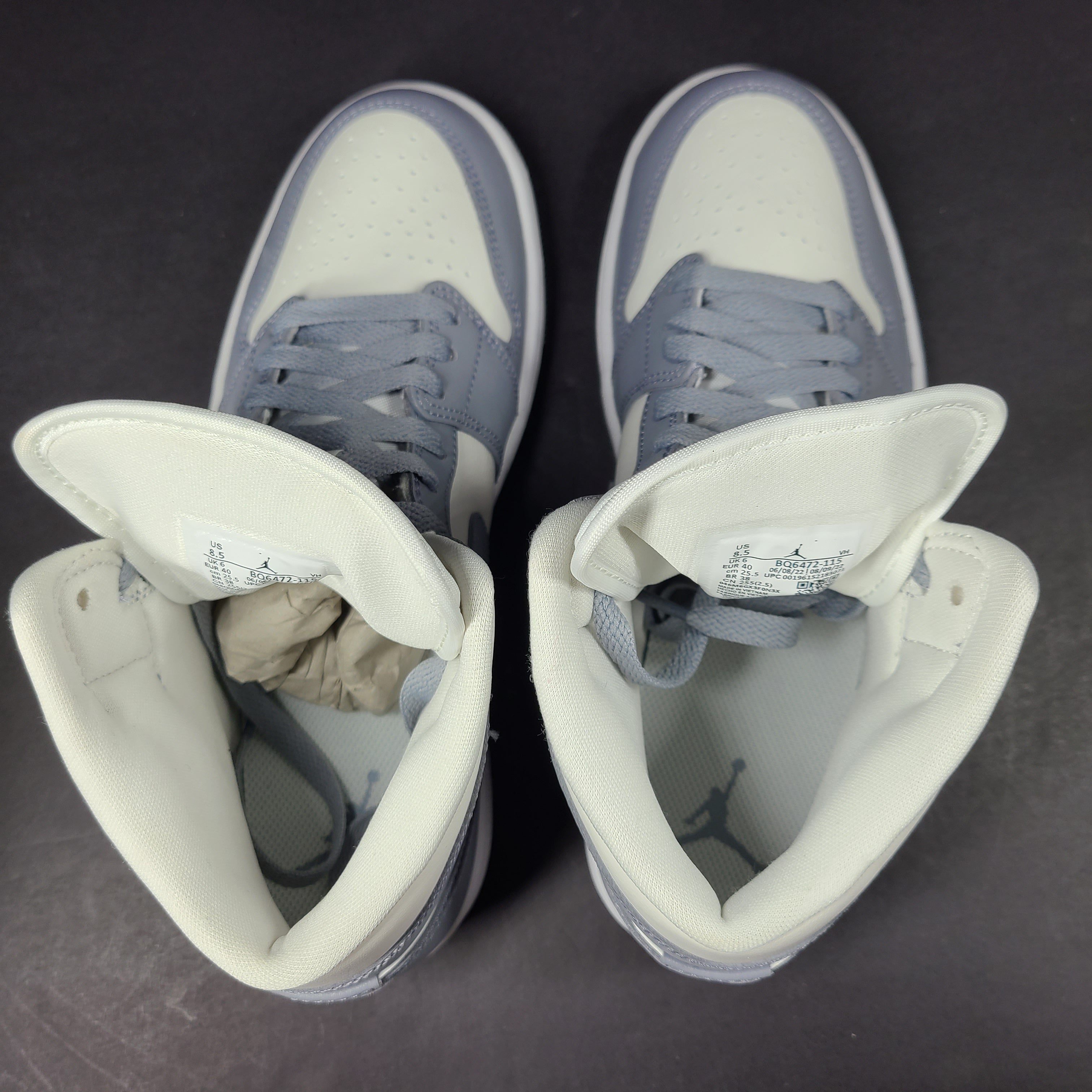 Nike Air Jordan 1 Mid in gray and white with a mid-top profile and classic Swoosh detailing for versatile streetwear styling.