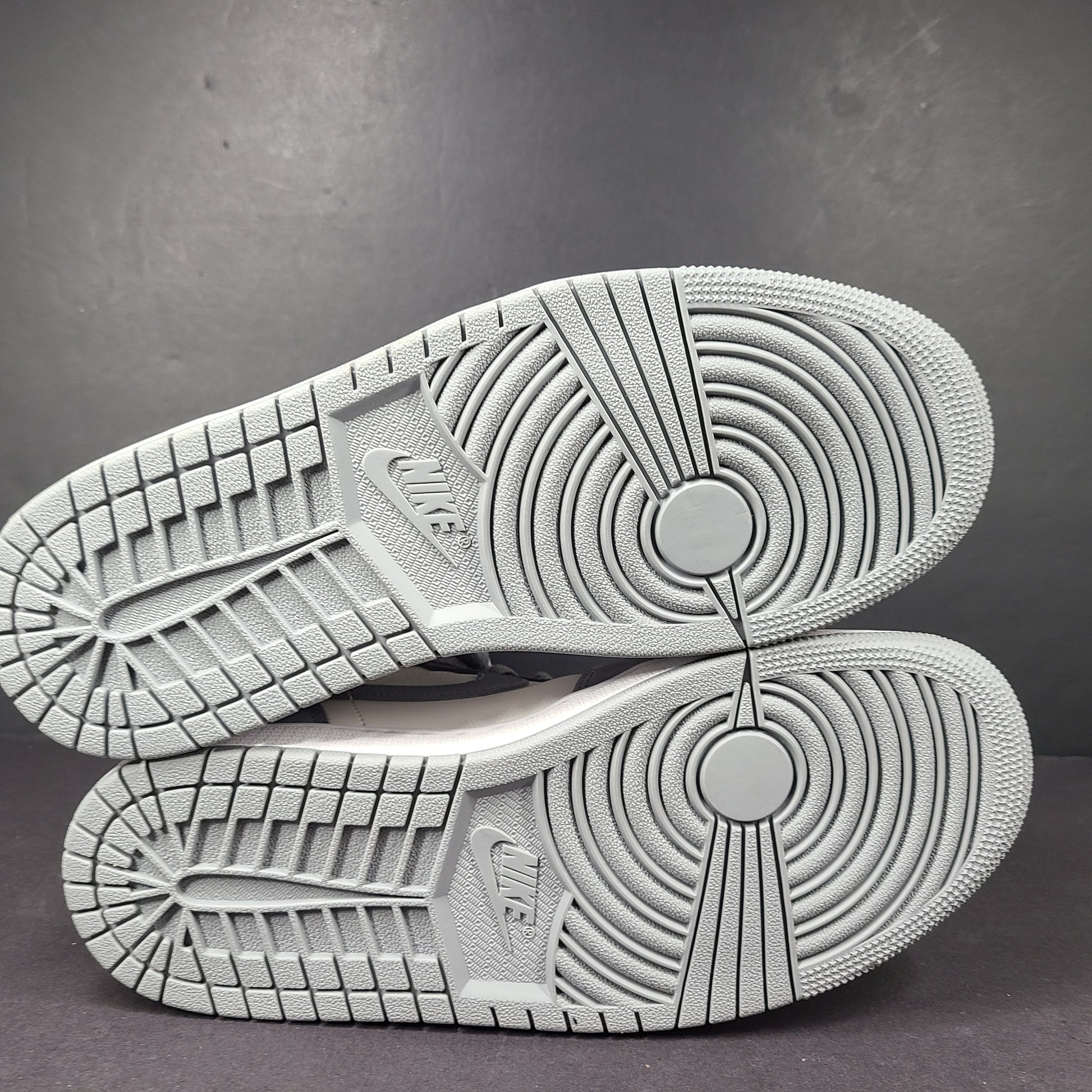 Nike Air Jordan 1 Mid in gray and white with a mid-top profile and classic Swoosh detailing for versatile streetwear styling.