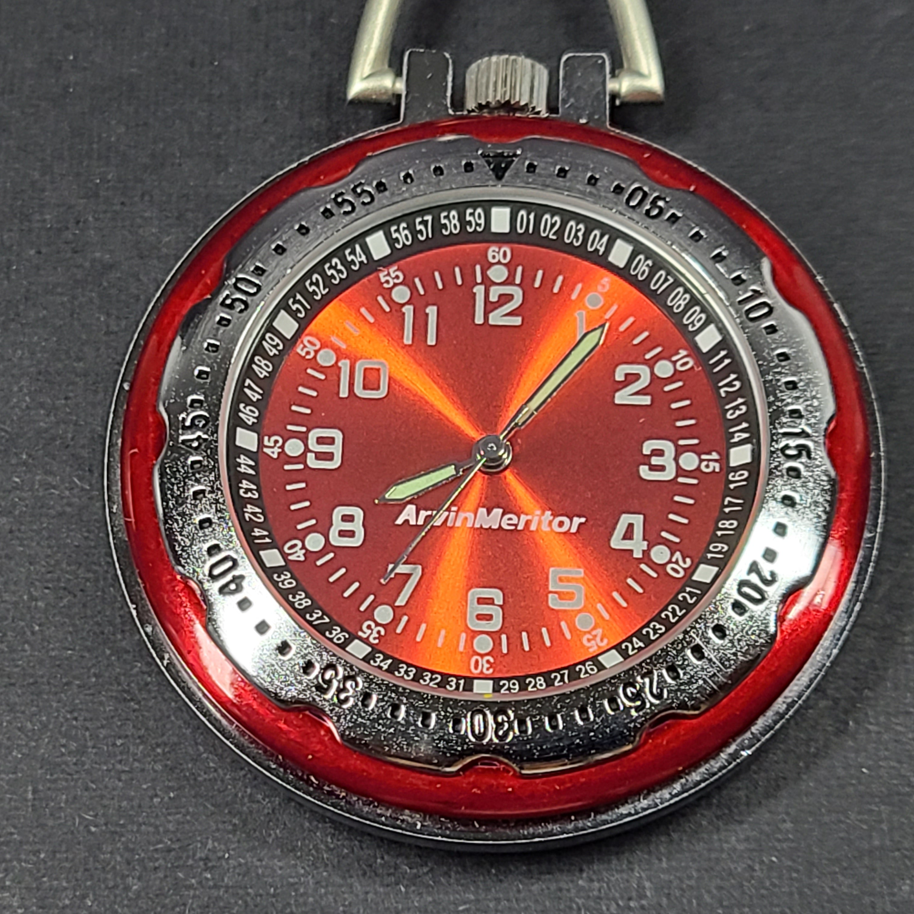 Red and silver pocket watch with a secure carabiner clip, slim profile, and durable construction for active use.
