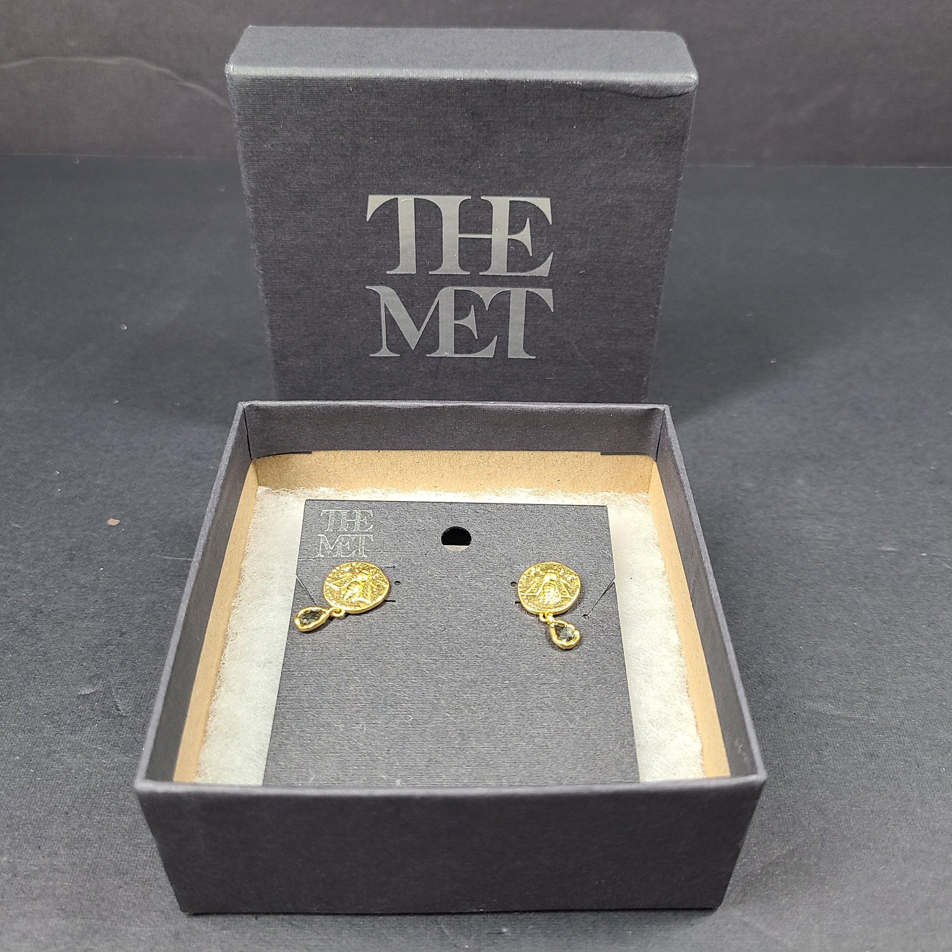 Gold Mediterranean coin stud earrings with secure posts and a timeless classical motif for everyday and evening wear.