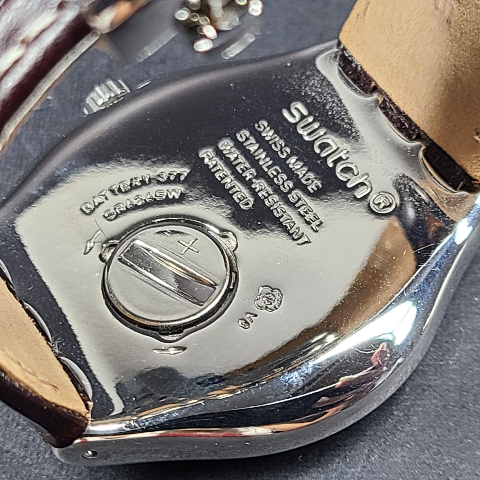Swatch YGS452G stainless steel wristwatch with a white dial and brown leather strap.