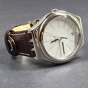 Swatch YGS452G stainless steel wristwatch with a white dial and brown leather strap.