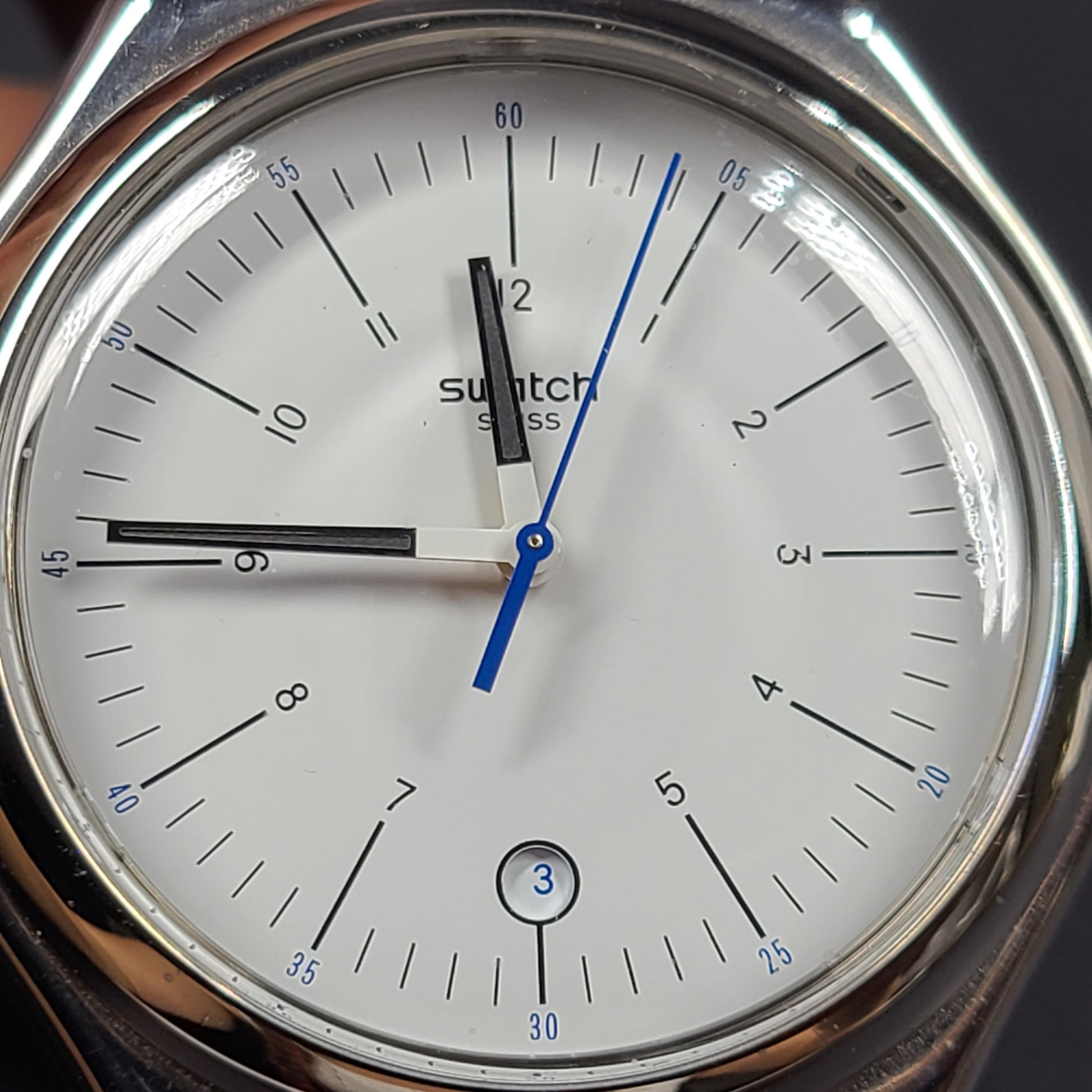 Swatch YGS452G stainless steel wristwatch with a white dial and brown leather strap.