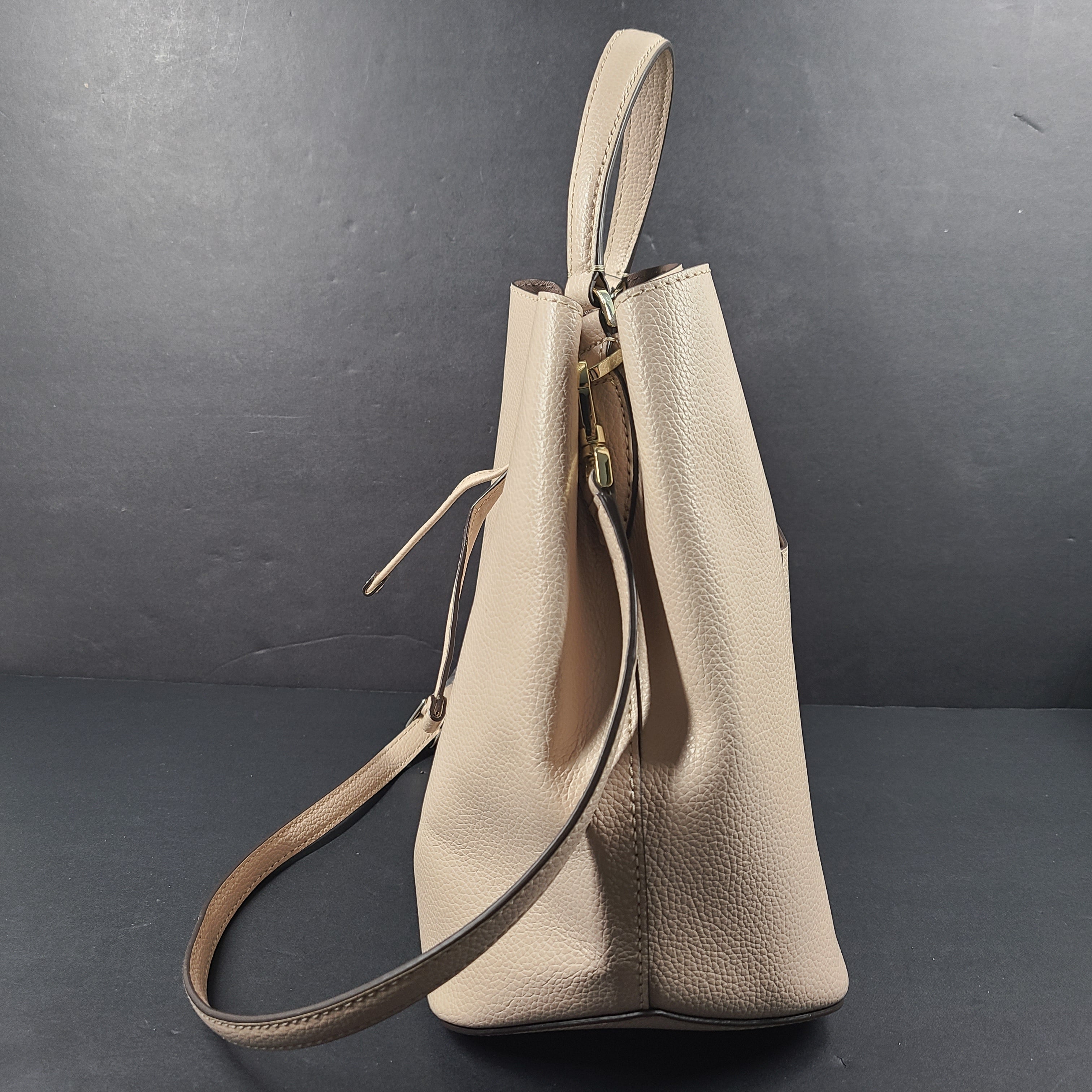 Beige Kate Spade handbag with intact price tag and protective plastic on the straps.