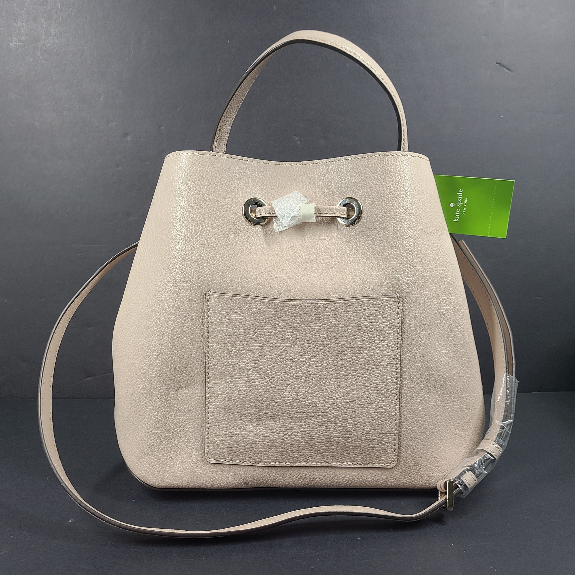 Beige Kate Spade handbag with intact price tag and protective plastic on the straps.