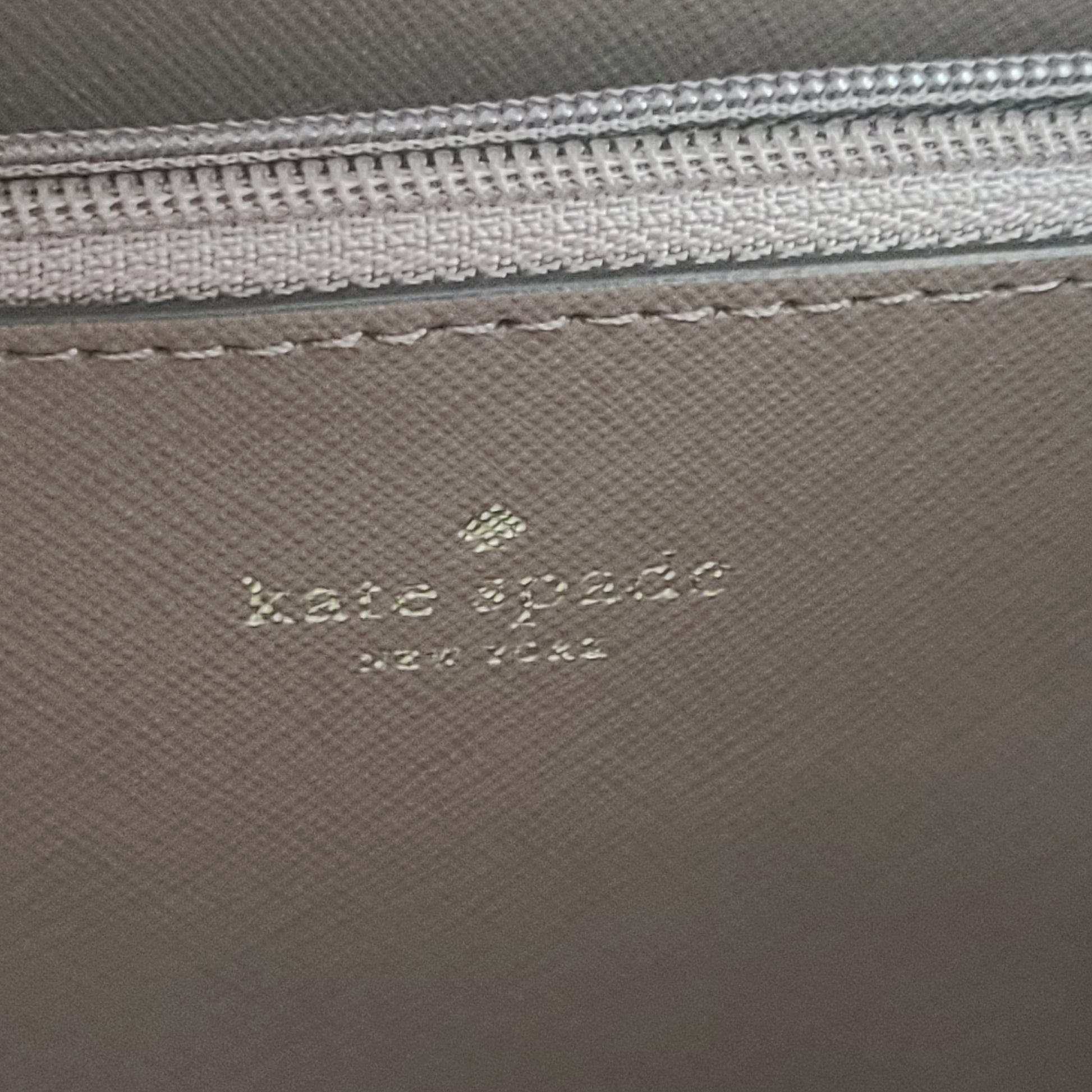 Beige Kate Spade handbag with intact price tag and protective plastic on the straps.