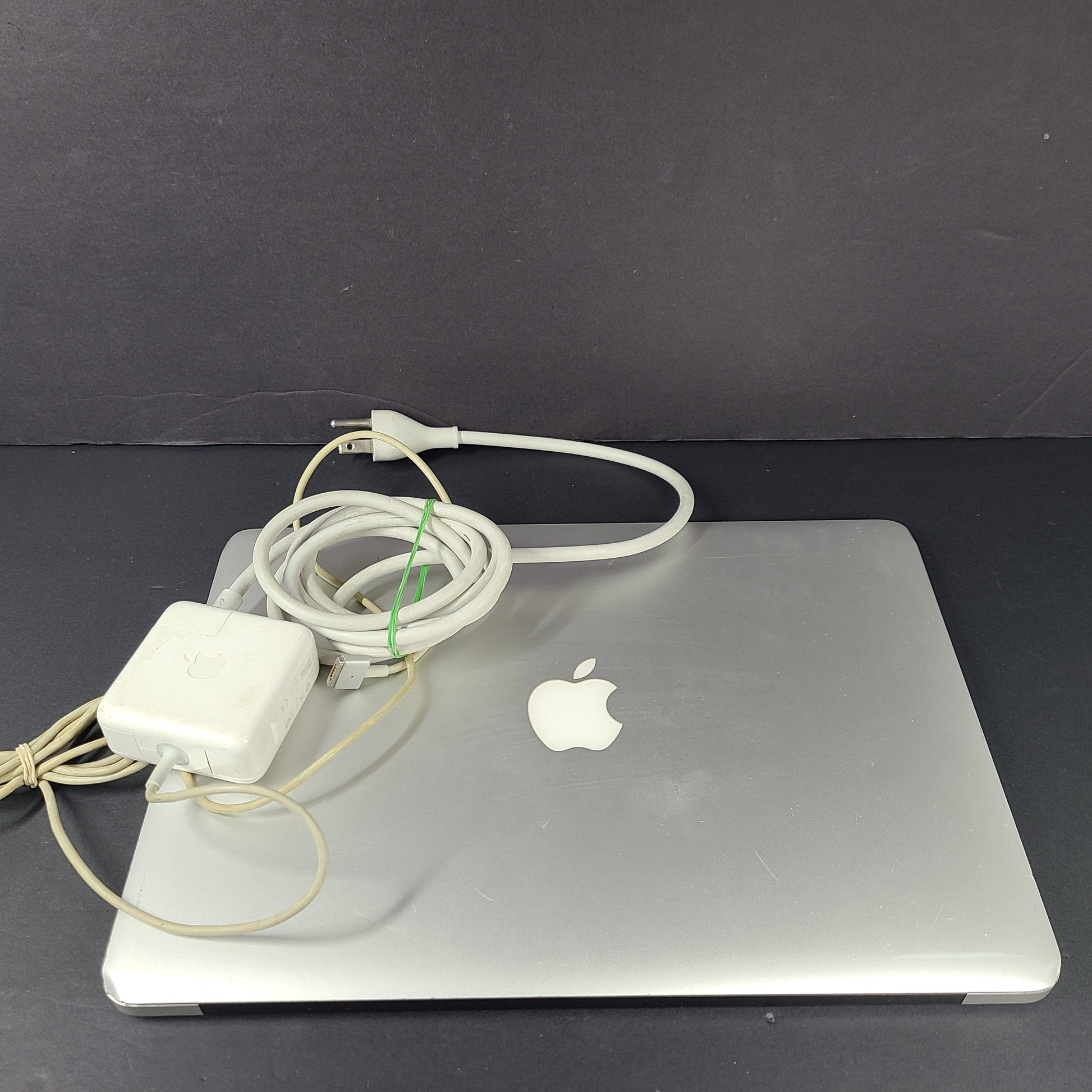 Silver Apple MacBook Air A1466 with body wear and a damaged screen, sold with a charger.