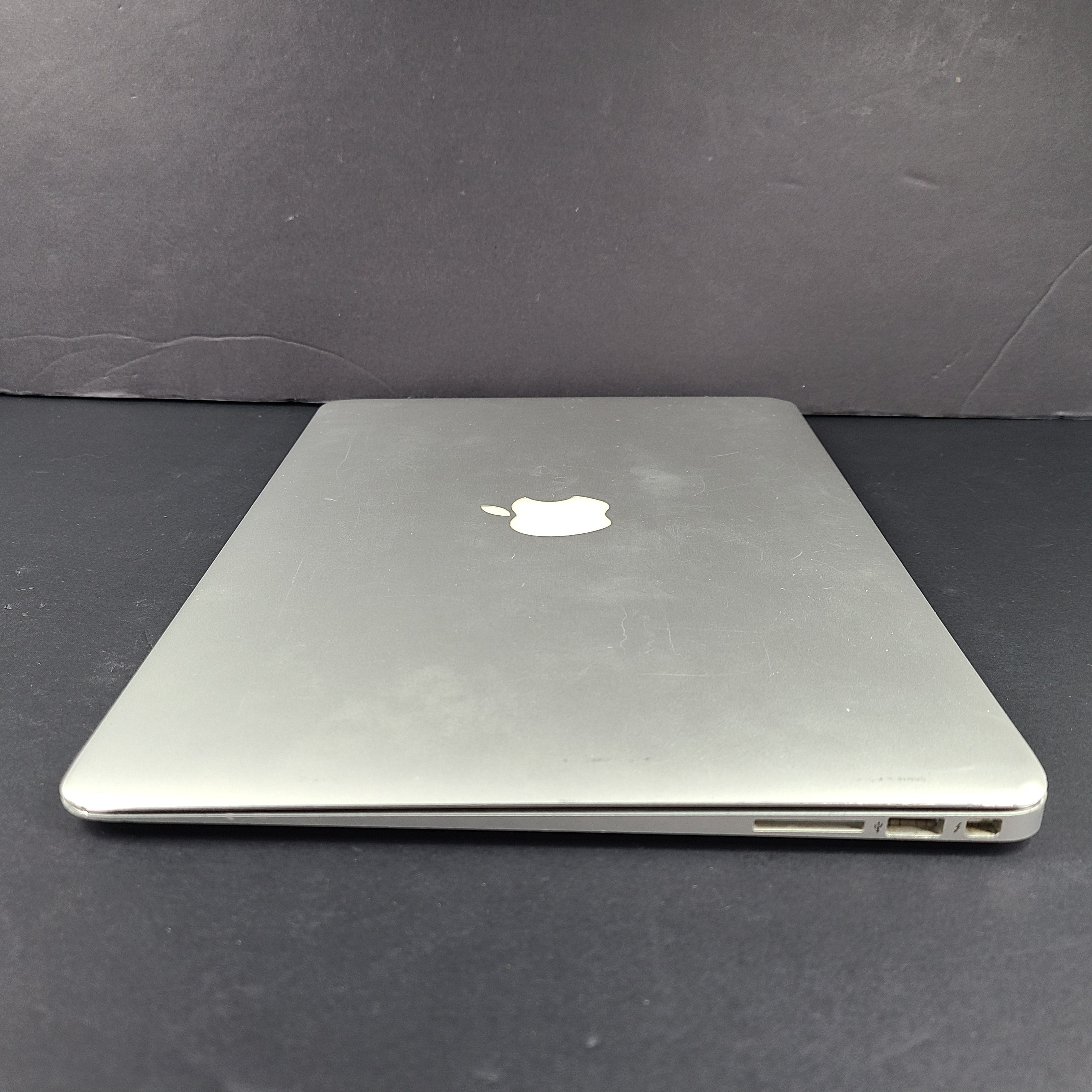Silver Apple MacBook Air A1466 with body wear and a damaged screen, sold with a charger.