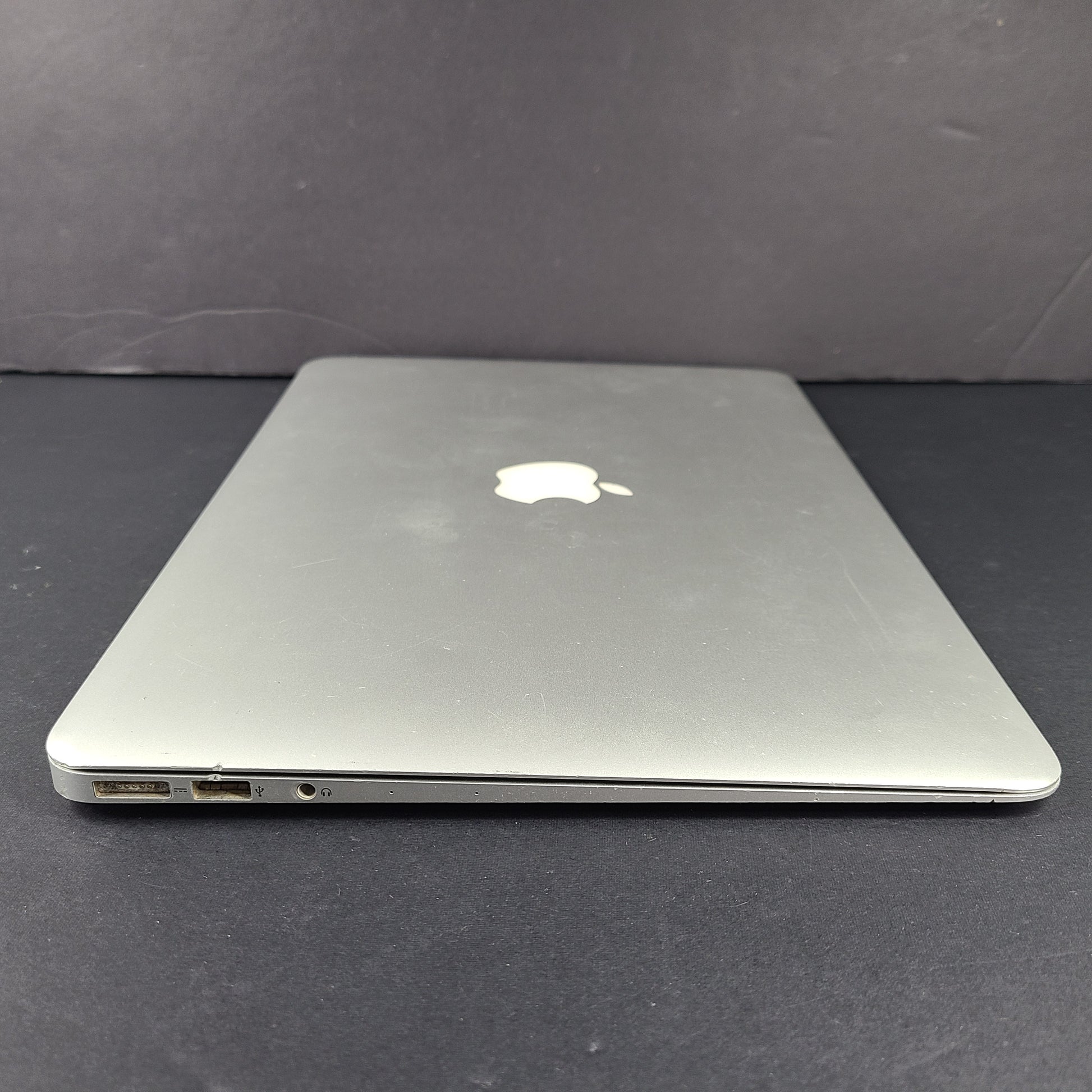 Silver Apple MacBook Air A1466 with body wear and a damaged screen, sold with a charger.