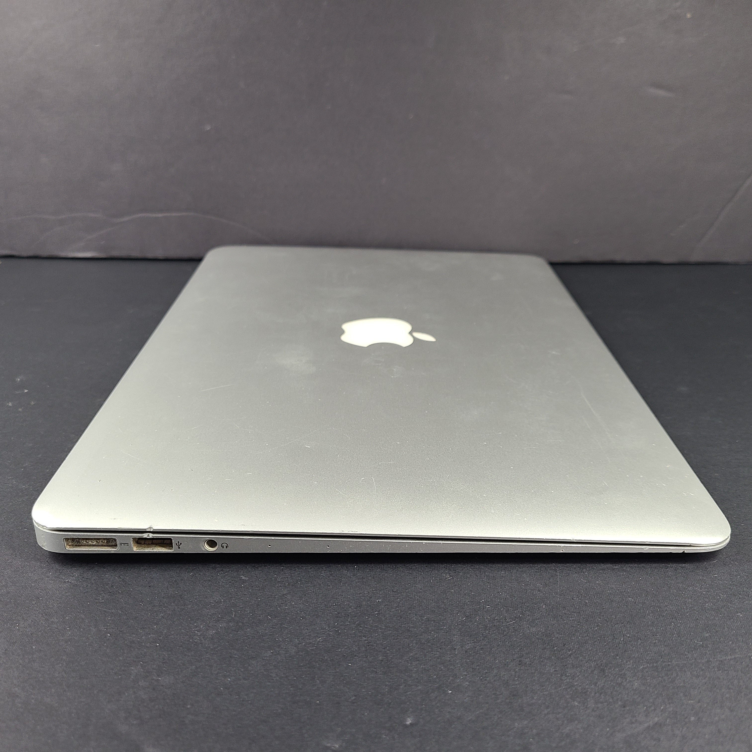 Silver Apple MacBook Air A1466 with body wear and a damaged screen, sold with a charger.