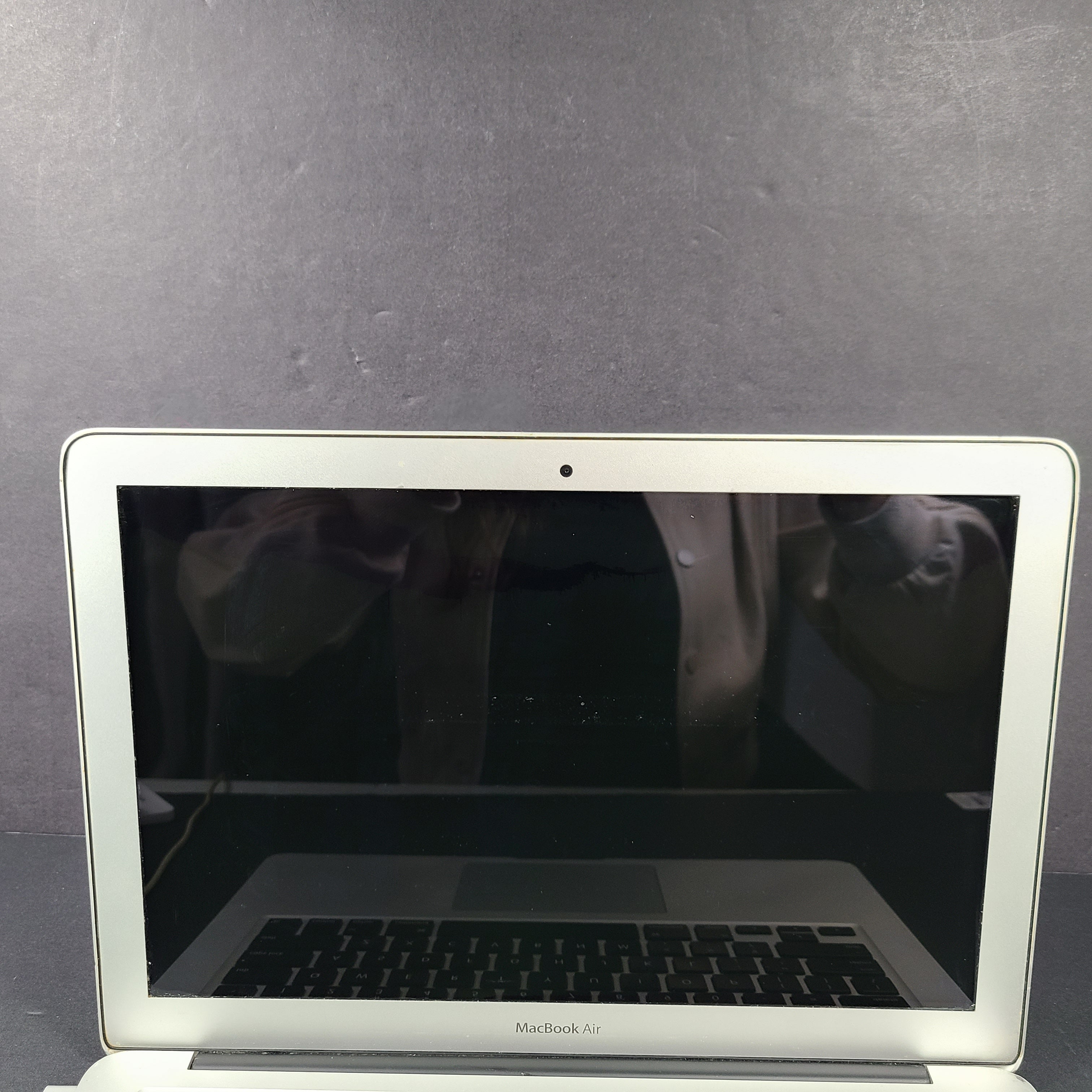 Silver Apple MacBook Air A1466 with body wear and a damaged screen, sold with a charger.