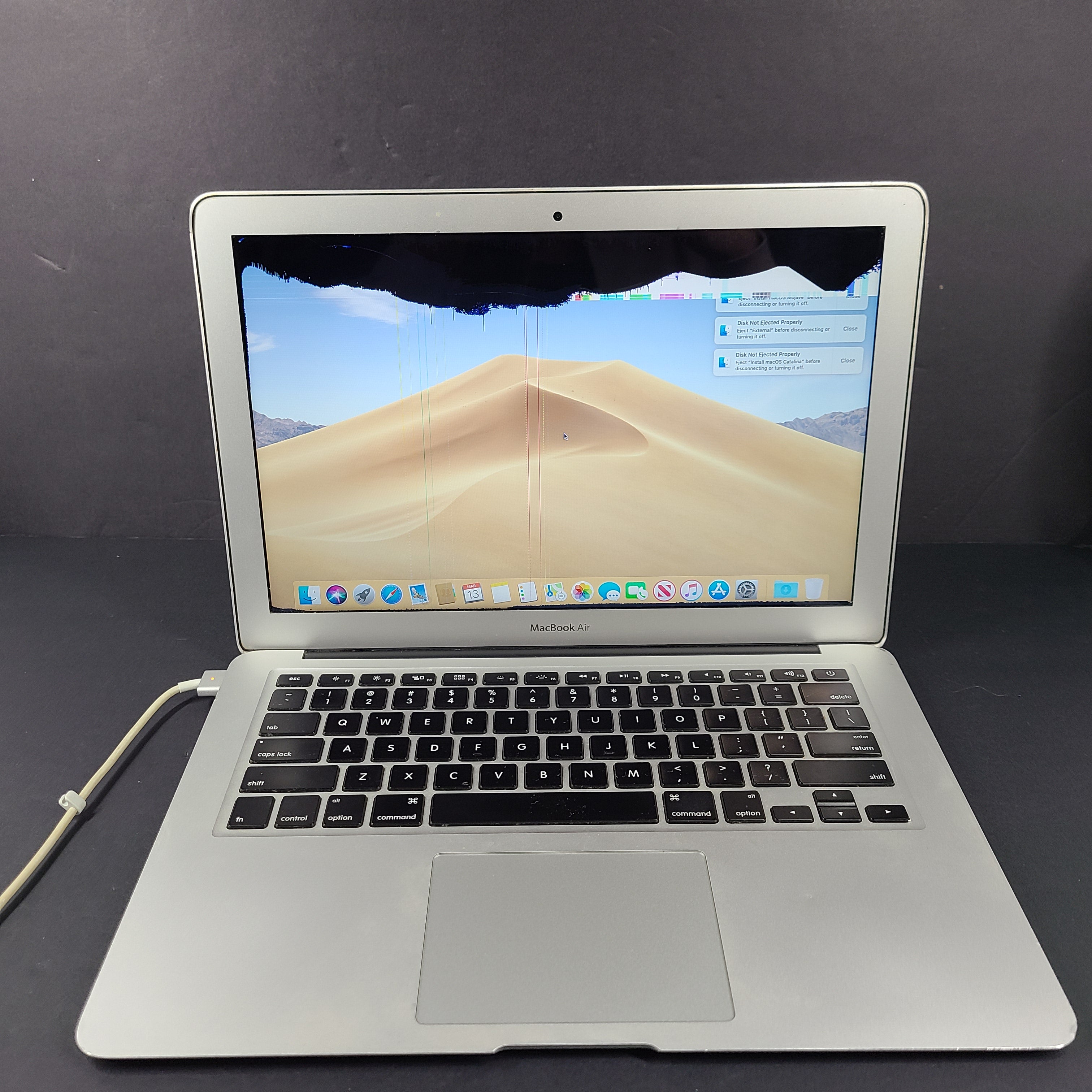 Silver Apple MacBook Air A1466 with body wear and a damaged screen, sold with a charger.