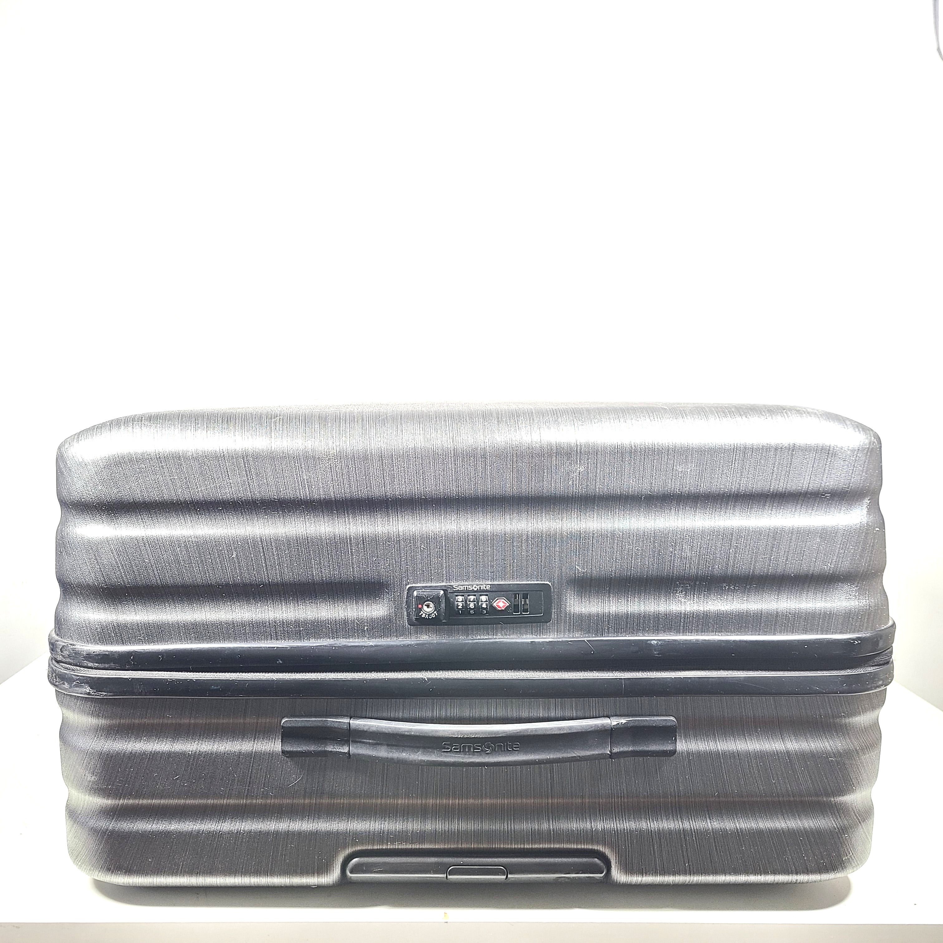 Black Samsonite Spinner 81/30 suitcase with scuffing on wheels and a clean interior.