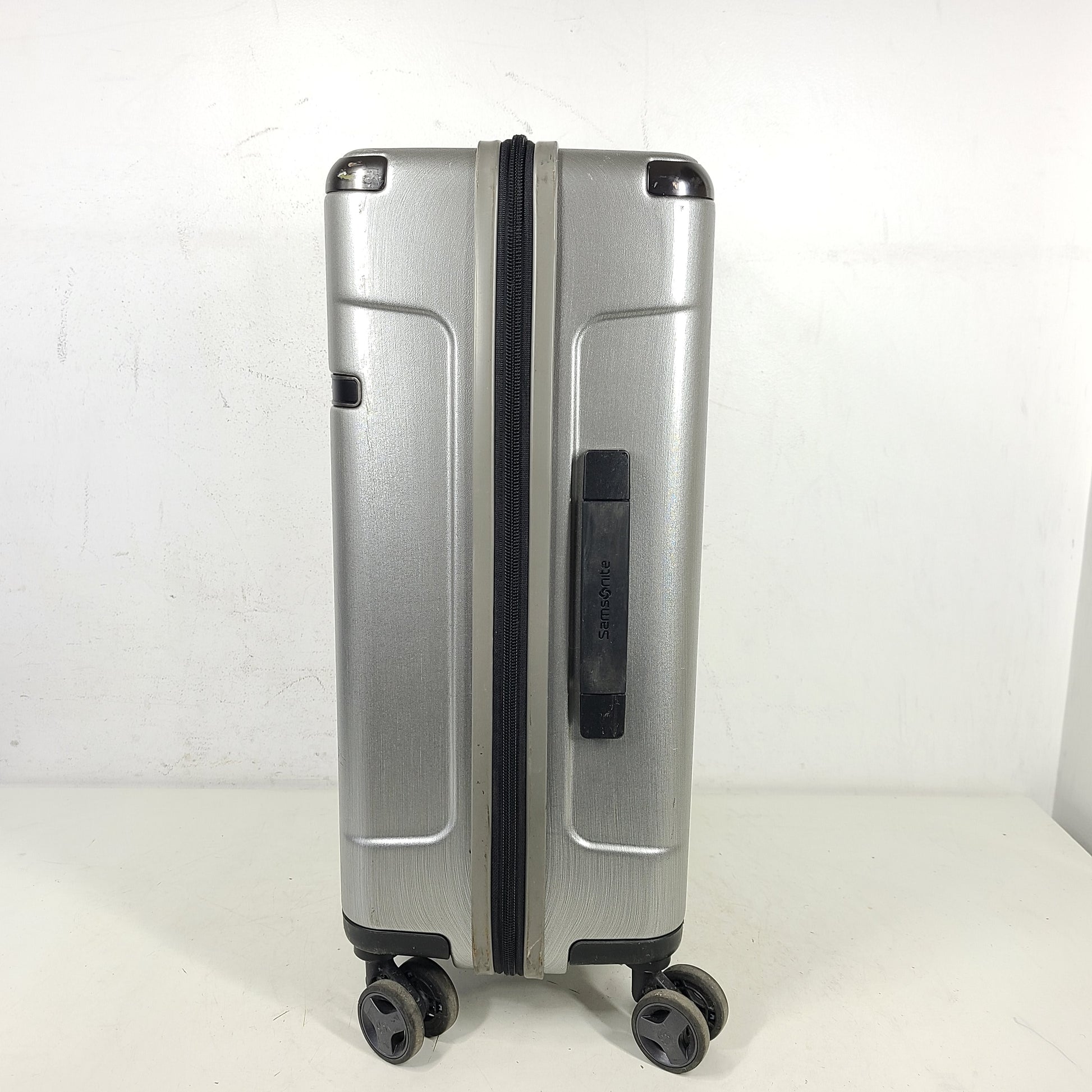 Silver Samsonite luggage with exterior branding on the handle and light exterior scratches; interior shows minimal wear.