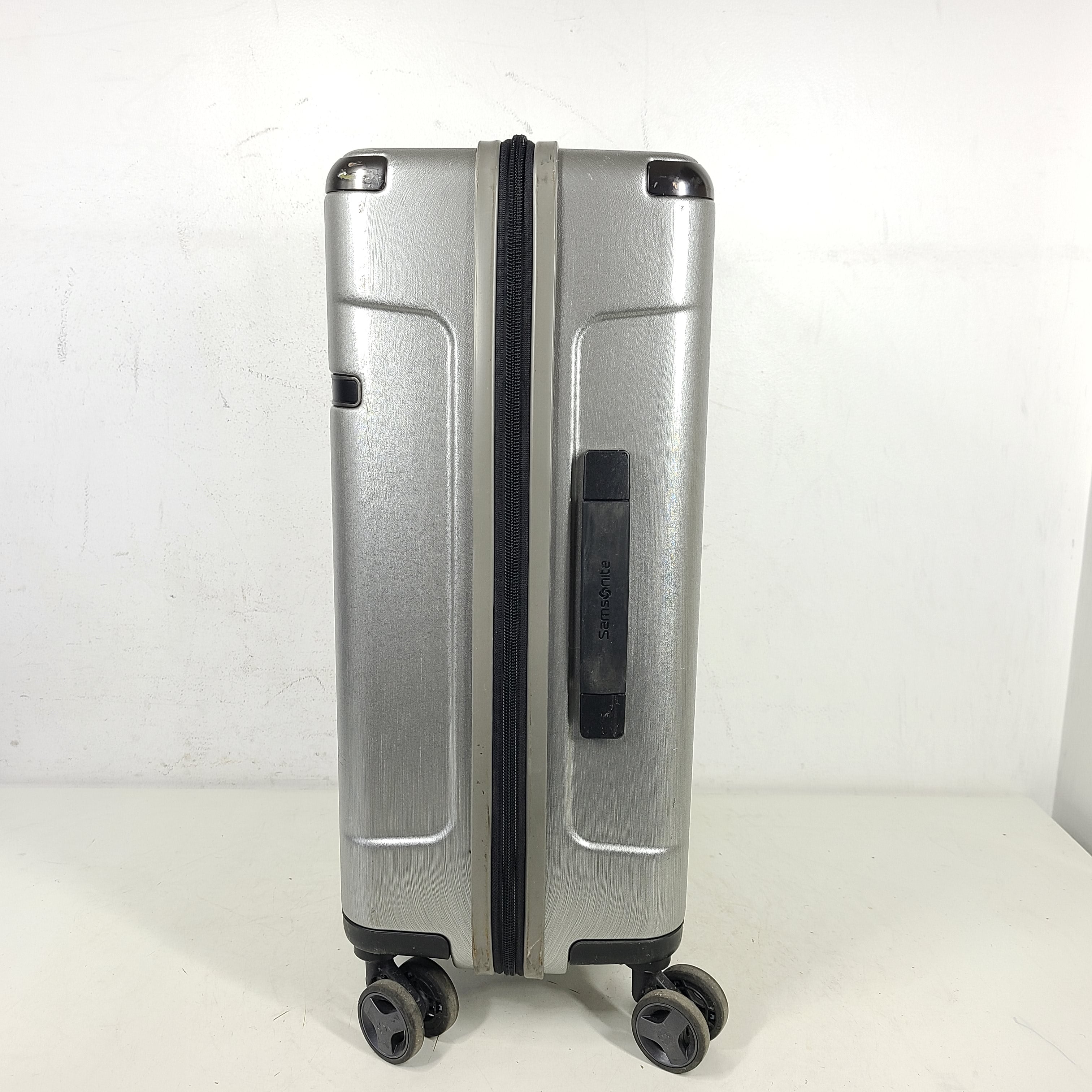 Silver Samsonite luggage with exterior branding on the handle and light exterior scratches; interior shows minimal wear.