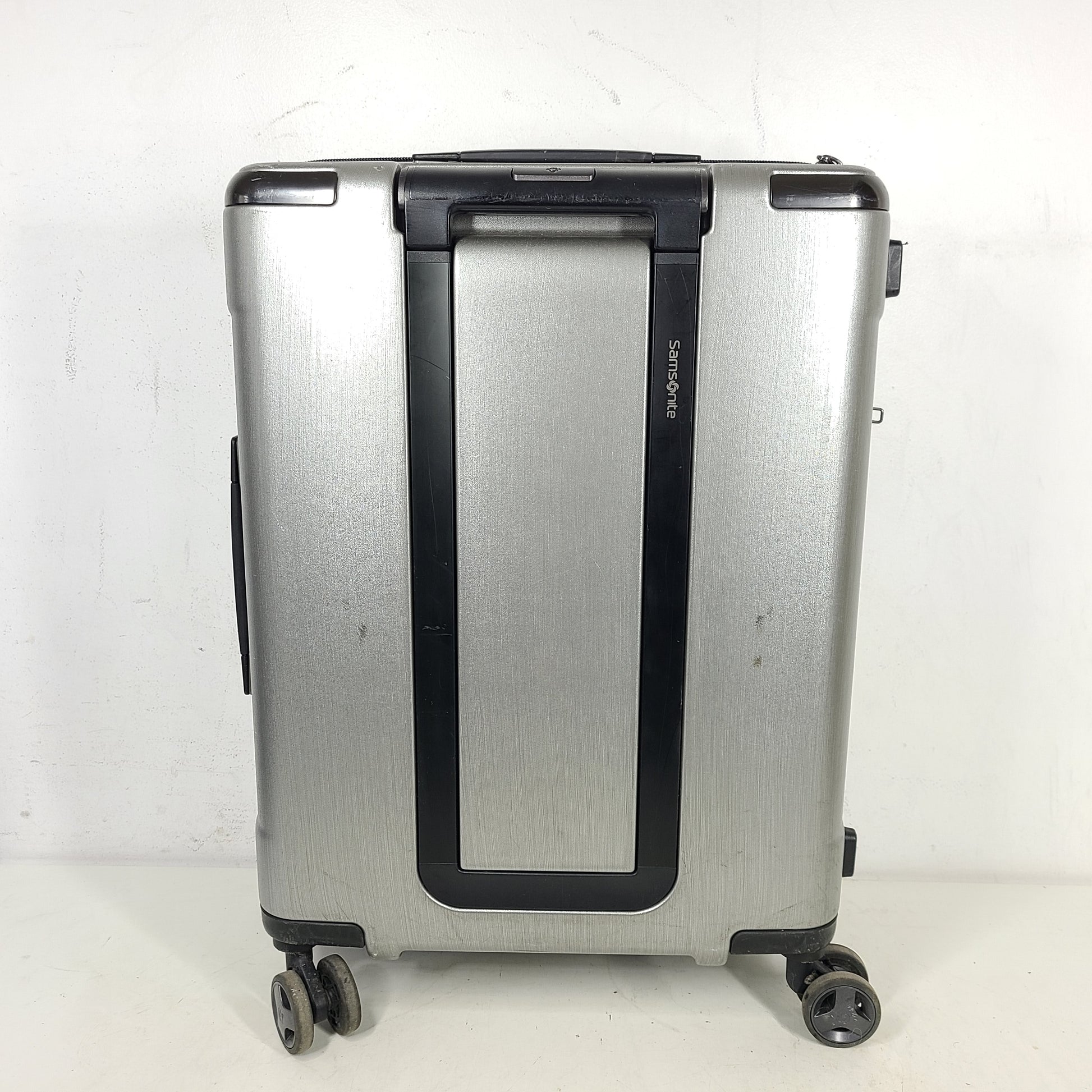 Silver Samsonite luggage with exterior branding on the handle and light exterior scratches; interior shows minimal wear.
