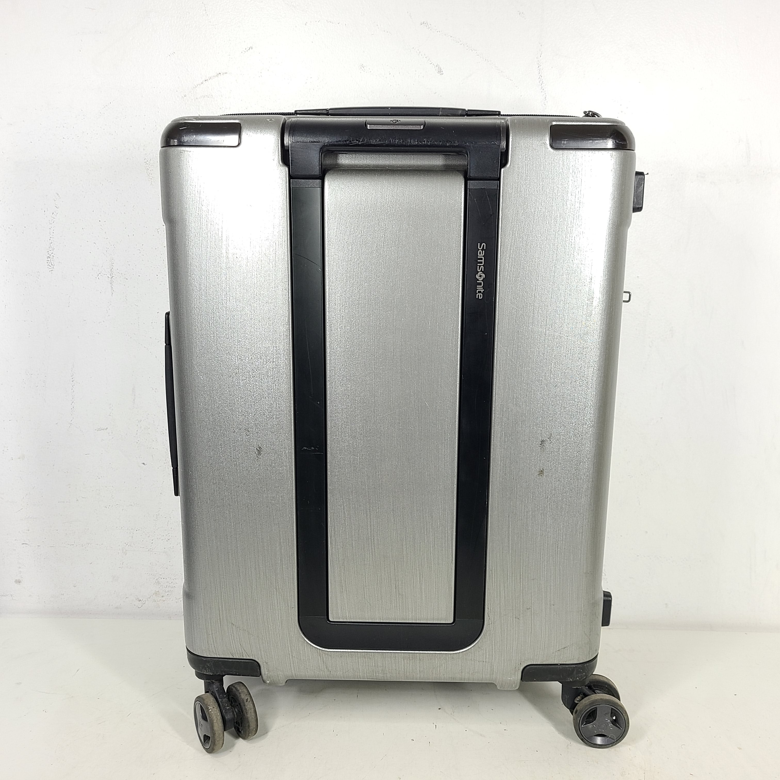 Silver Samsonite luggage with exterior branding on the handle and light exterior scratches; interior shows minimal wear.