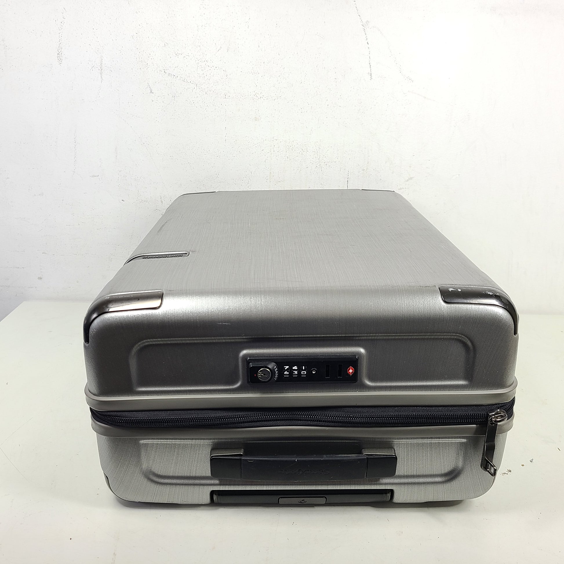 Silver Samsonite luggage with exterior branding on the handle and light exterior scratches; interior shows minimal wear.