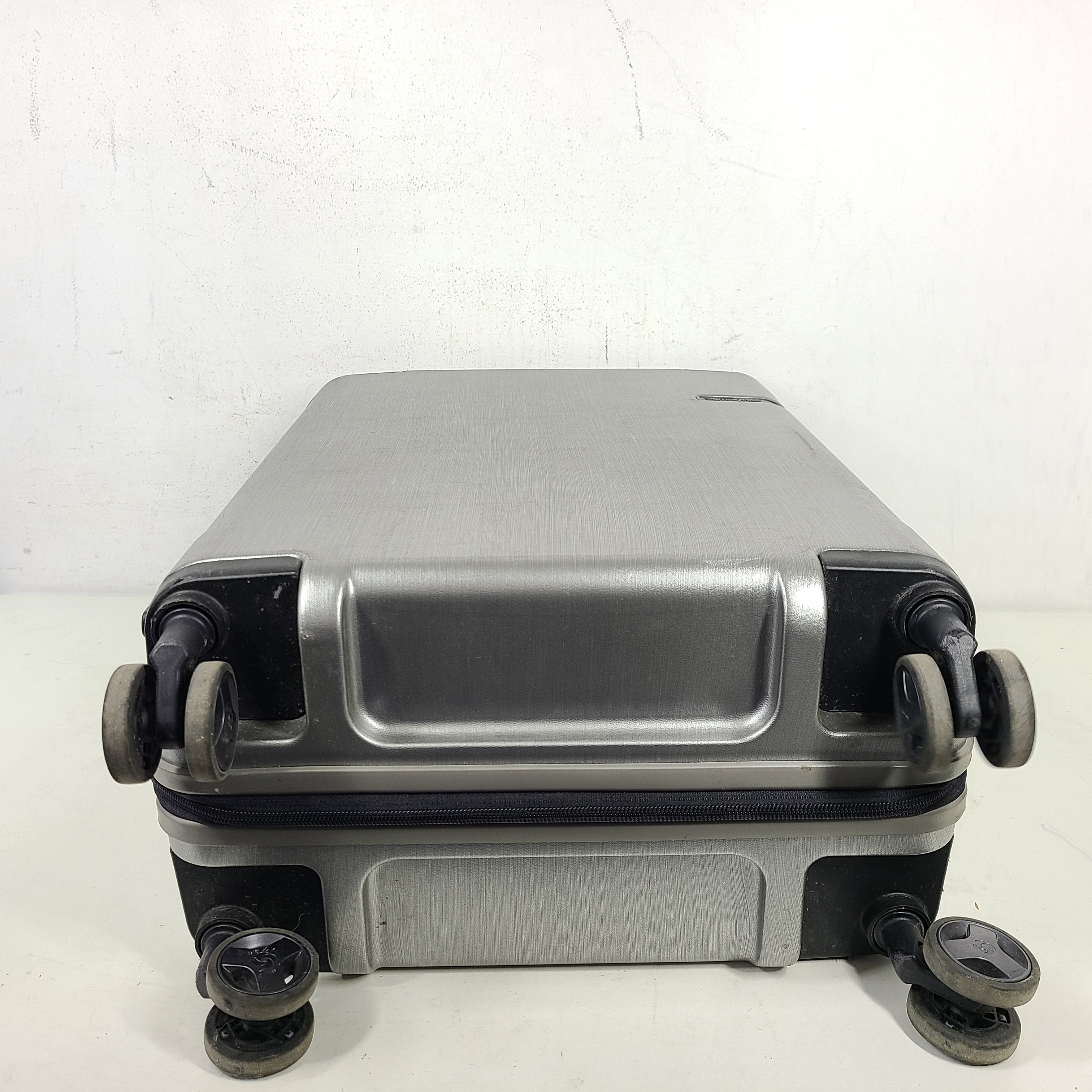 Silver Samsonite luggage with exterior branding on the handle and light exterior scratches; interior shows minimal wear.