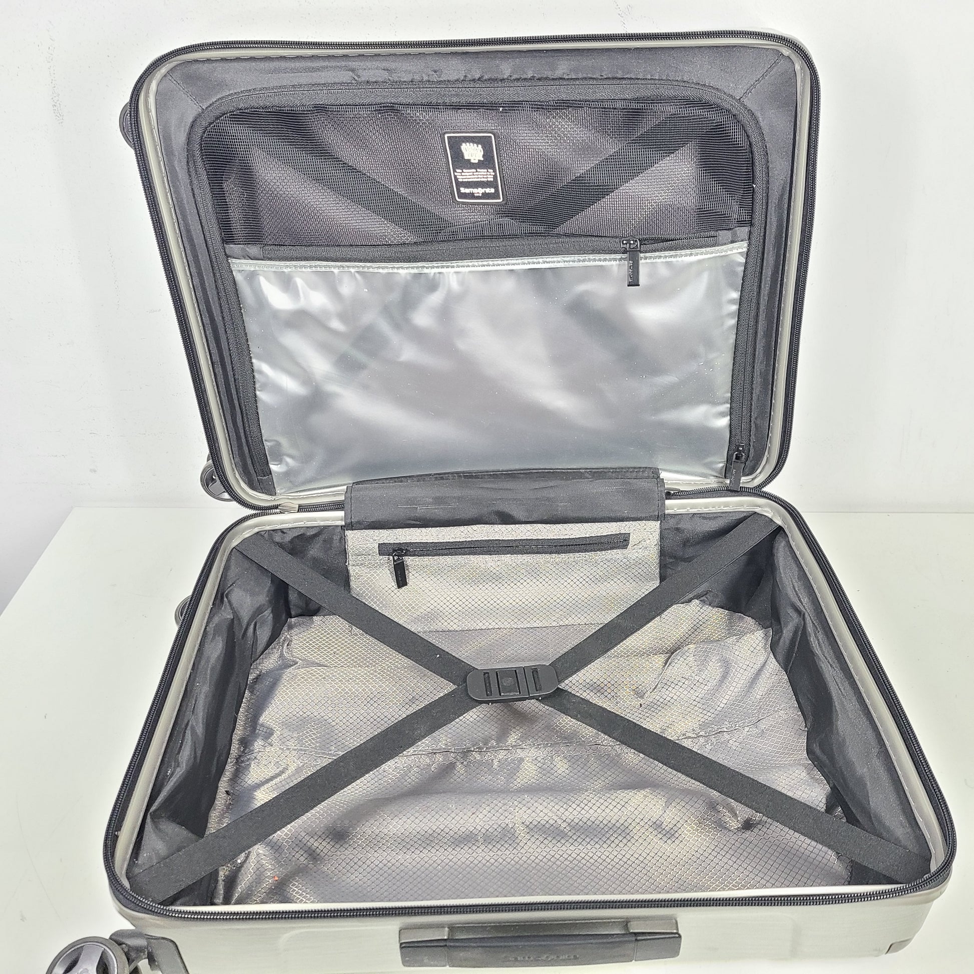 Silver Samsonite luggage with exterior branding on the handle and light exterior scratches; interior shows minimal wear.