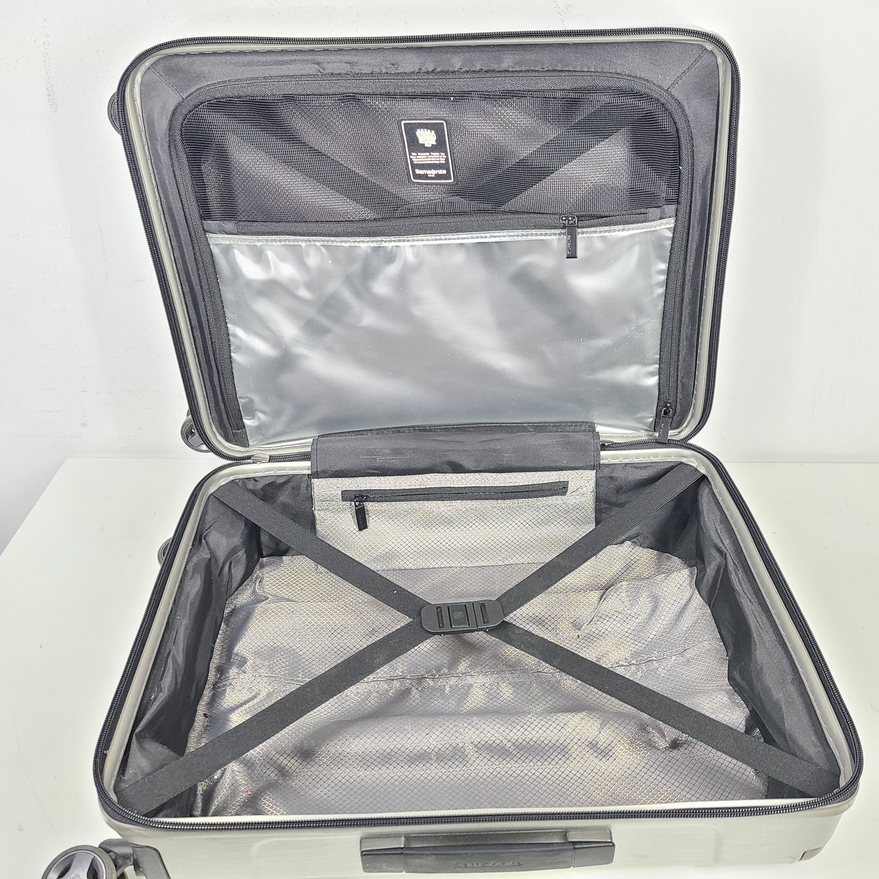 Silver Samsonite luggage with exterior branding on the handle and light exterior scratches; interior shows minimal wear.