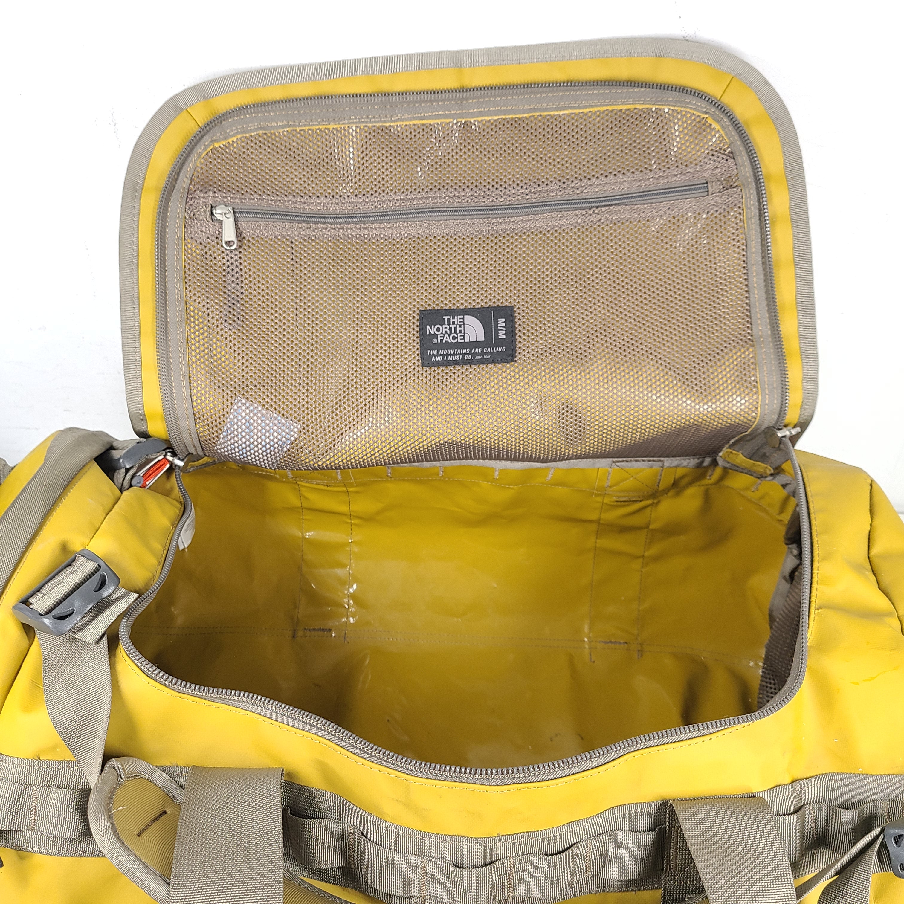 The North Face medium Base Camp duffel in yellow and grey with reinforced handles and adjustable shoulder straps.