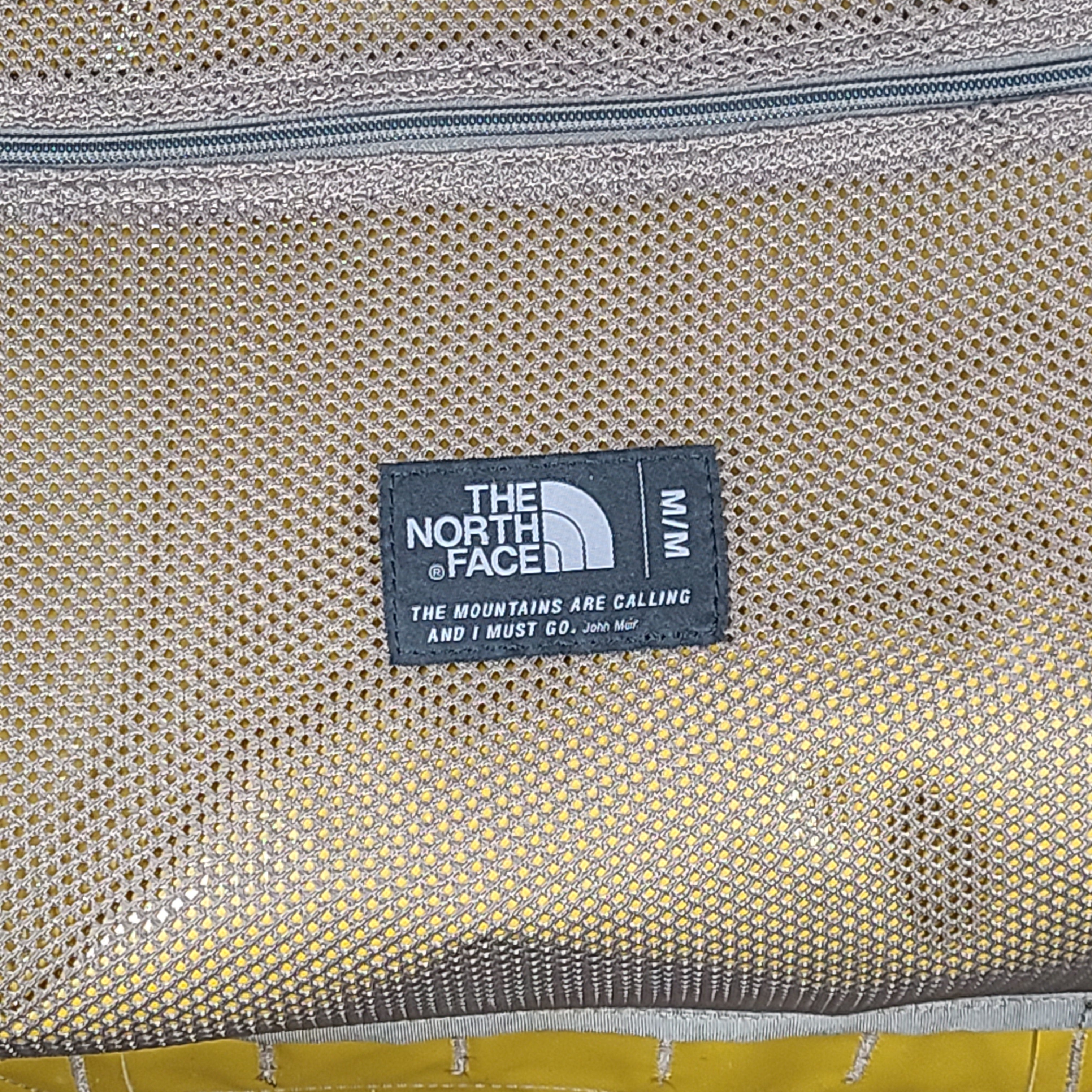 The North Face medium Base Camp duffel in yellow and grey with reinforced handles and adjustable shoulder straps.