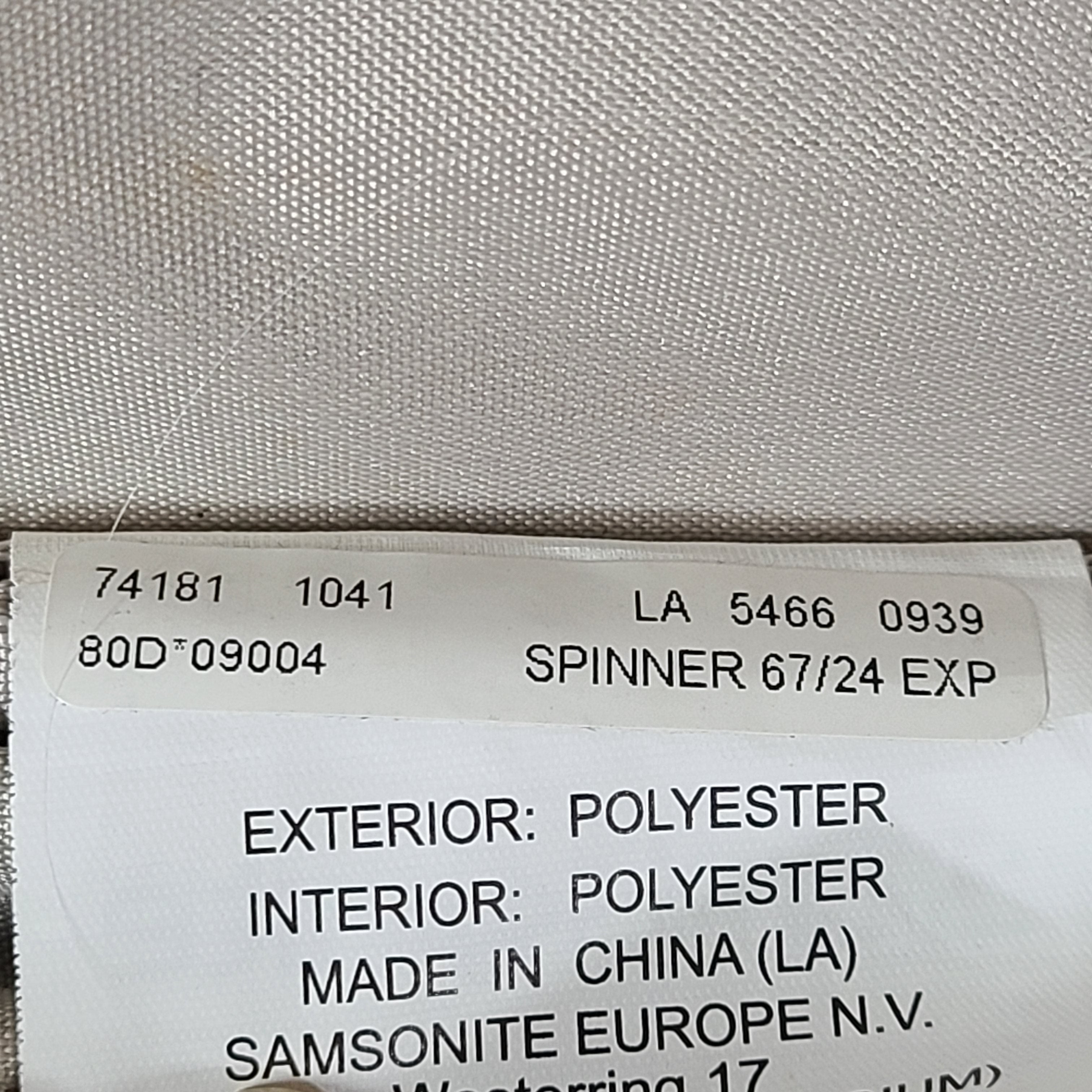 Black Samsonite 67/24 EXP spinner suitcase with scuffs and marks on the exterior.