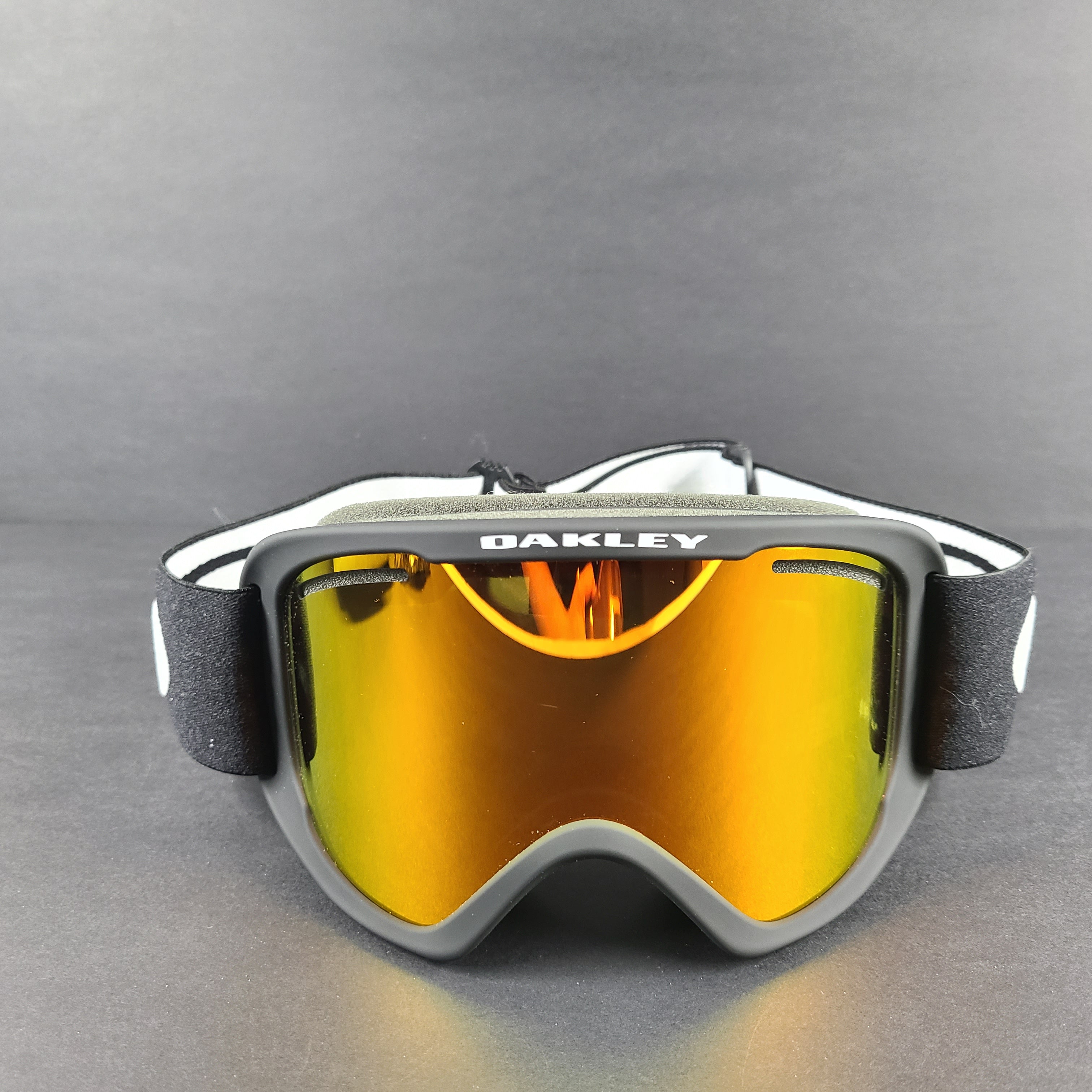 Oakley black snow goggles feature an orange lens and include an extra replacement lens and storage bag.