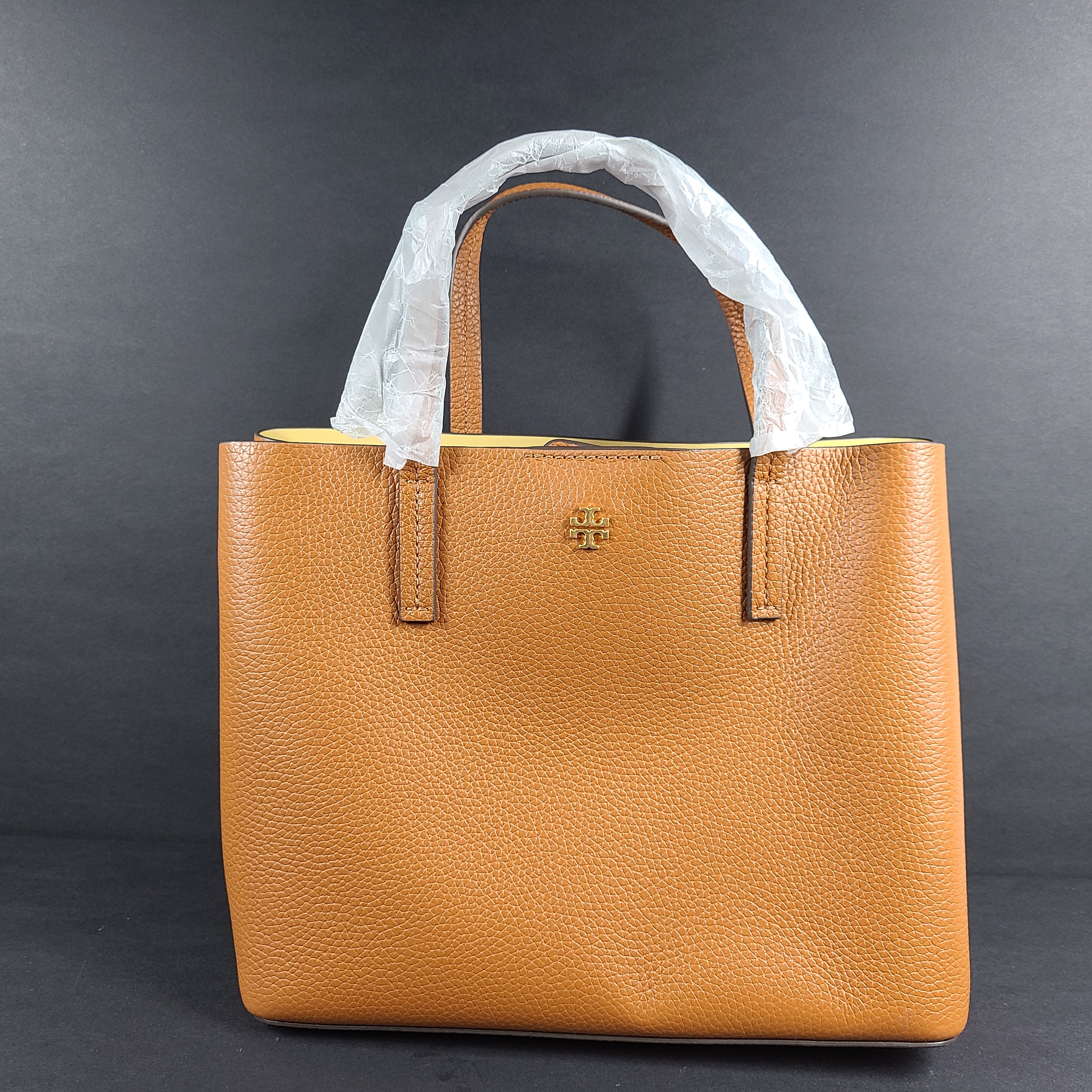Tory Burch brown leather handbag with a detachable shoulder strap and protective-wrapped handles.