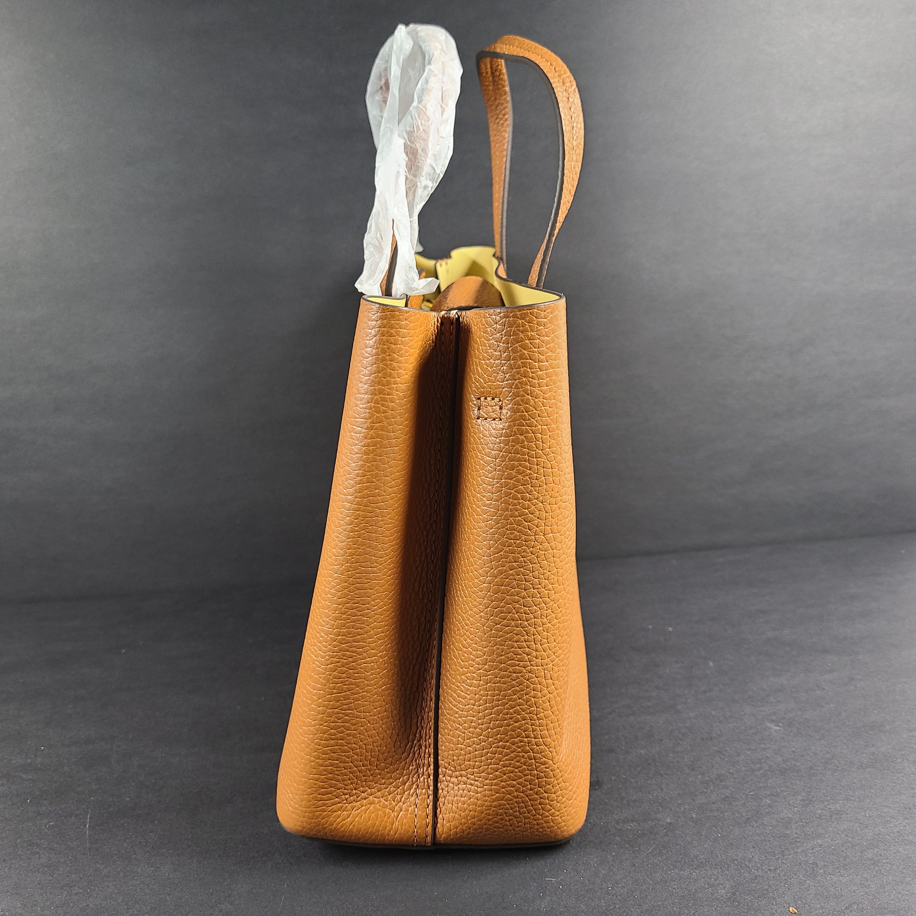 Tory Burch brown leather handbag with a detachable shoulder strap and protective-wrapped handles.