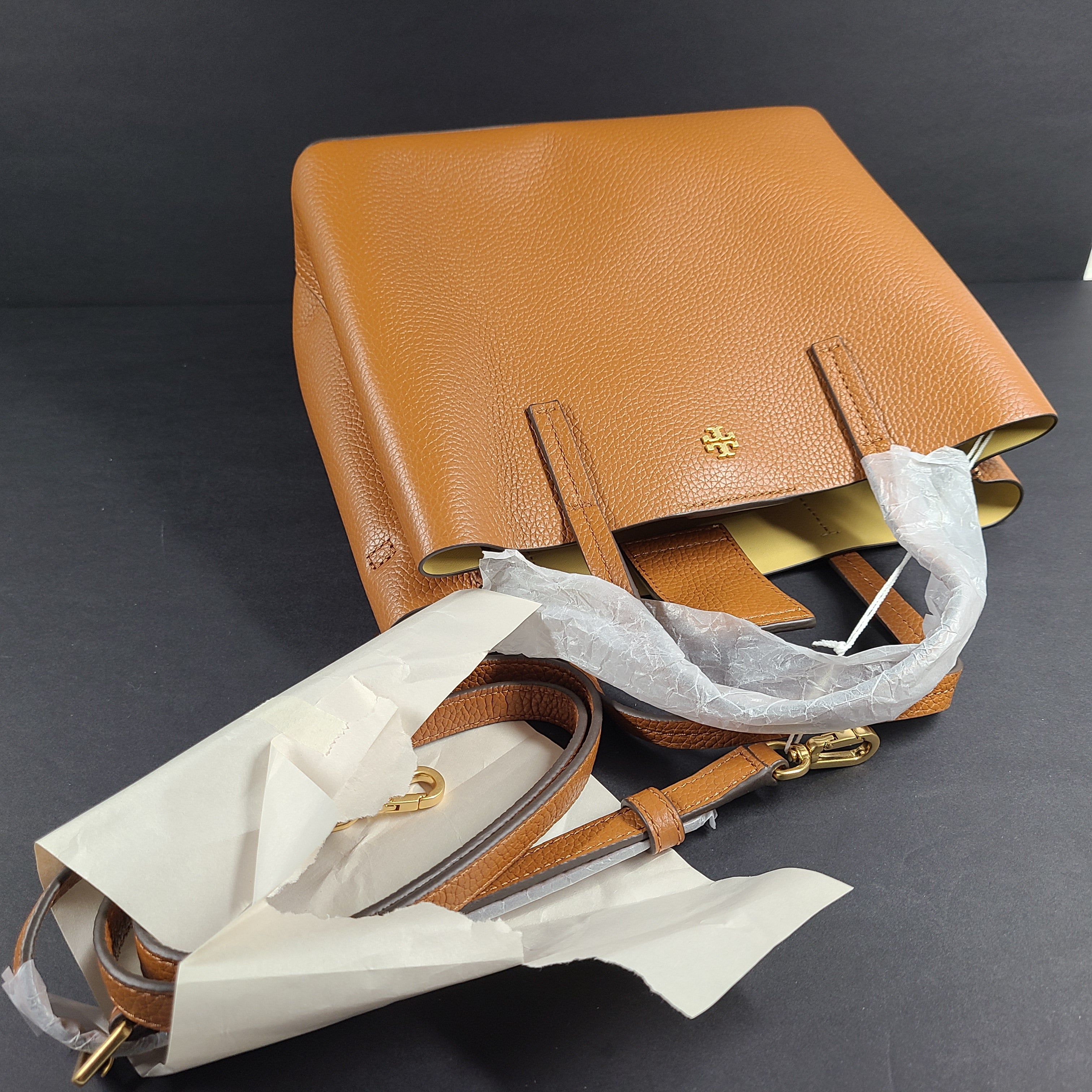 Tory Burch brown leather handbag with a detachable shoulder strap and protective-wrapped handles.