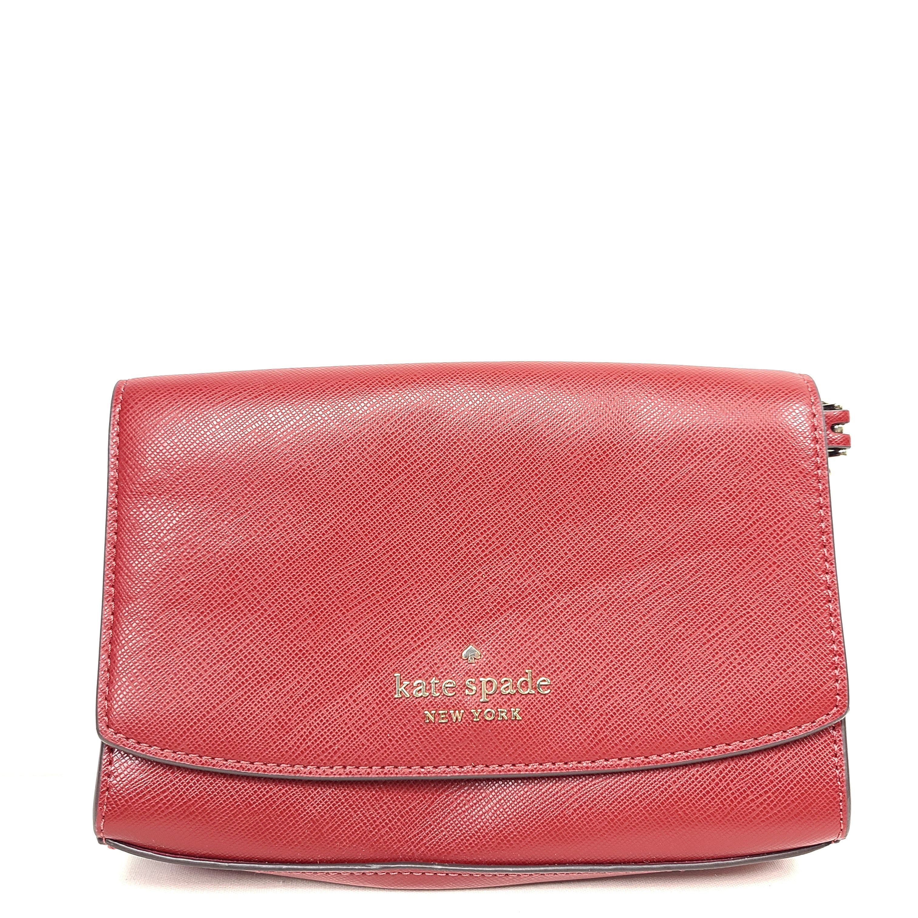 Red Kate Spade New York crossbody bag with an attached strap and internal compartments.