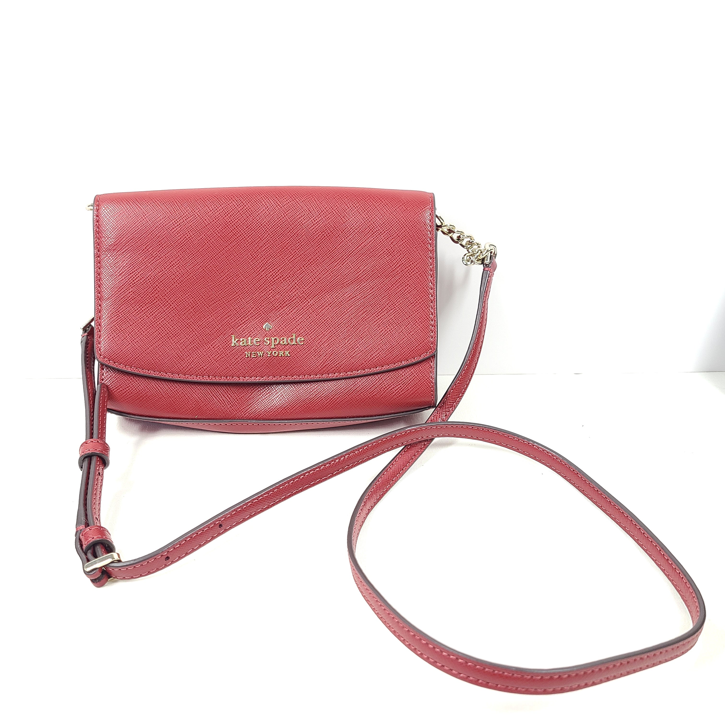 Red Kate Spade New York crossbody bag with an attached strap and internal compartments.