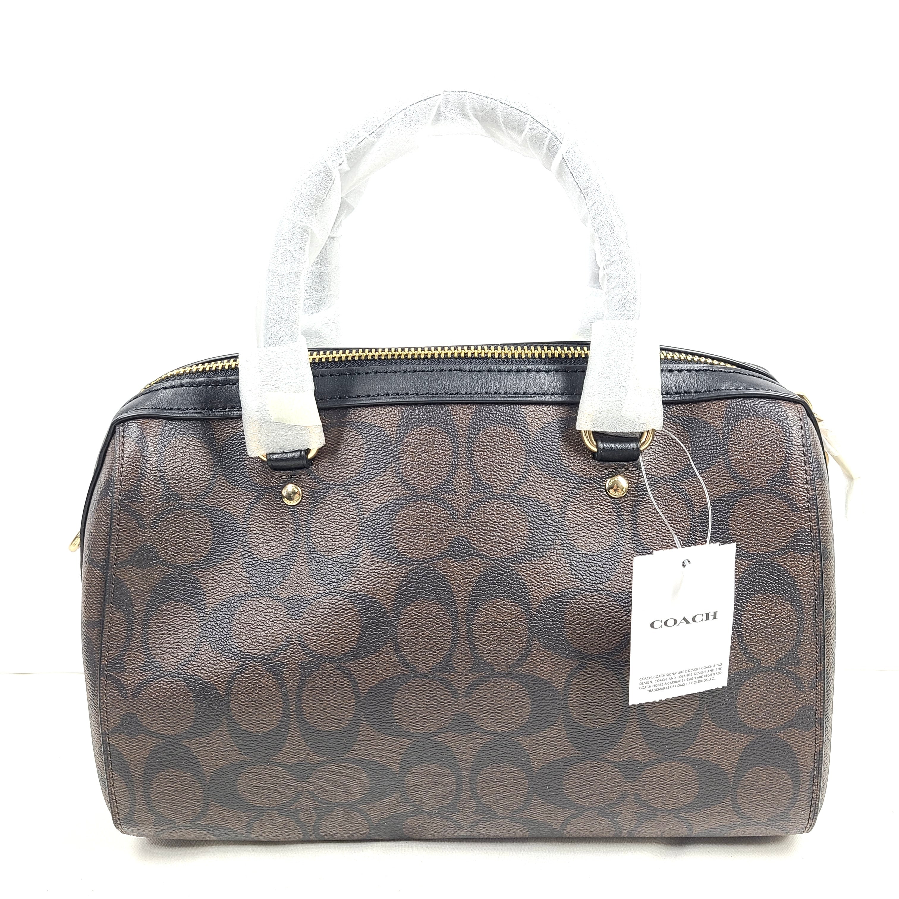 Coach brown signature-print handbag with black accents, including an interior label with the model number.