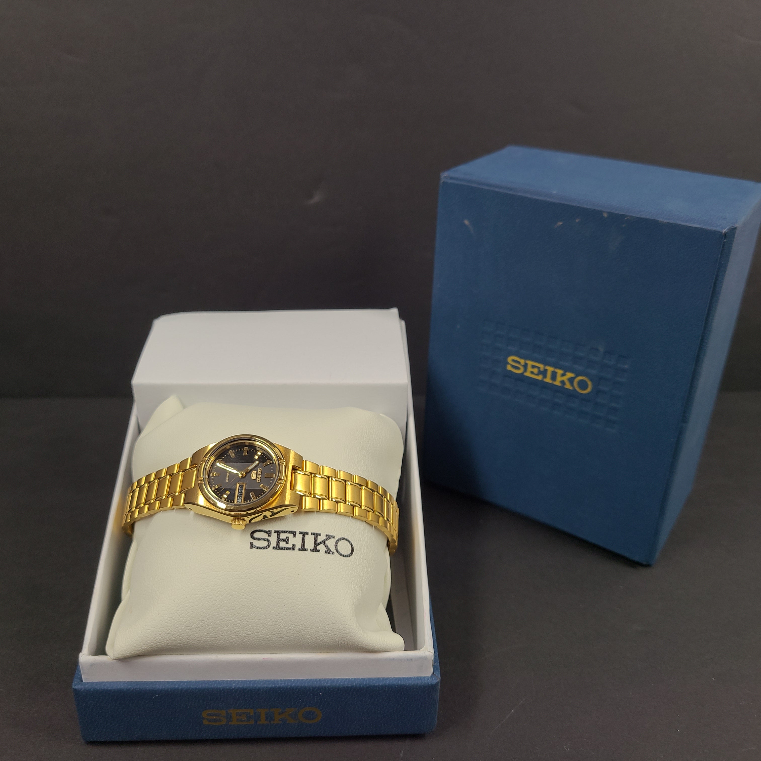 Gold-tone Seiko 5 automatic ladies watch with a black dial and stainless steel bracelet.