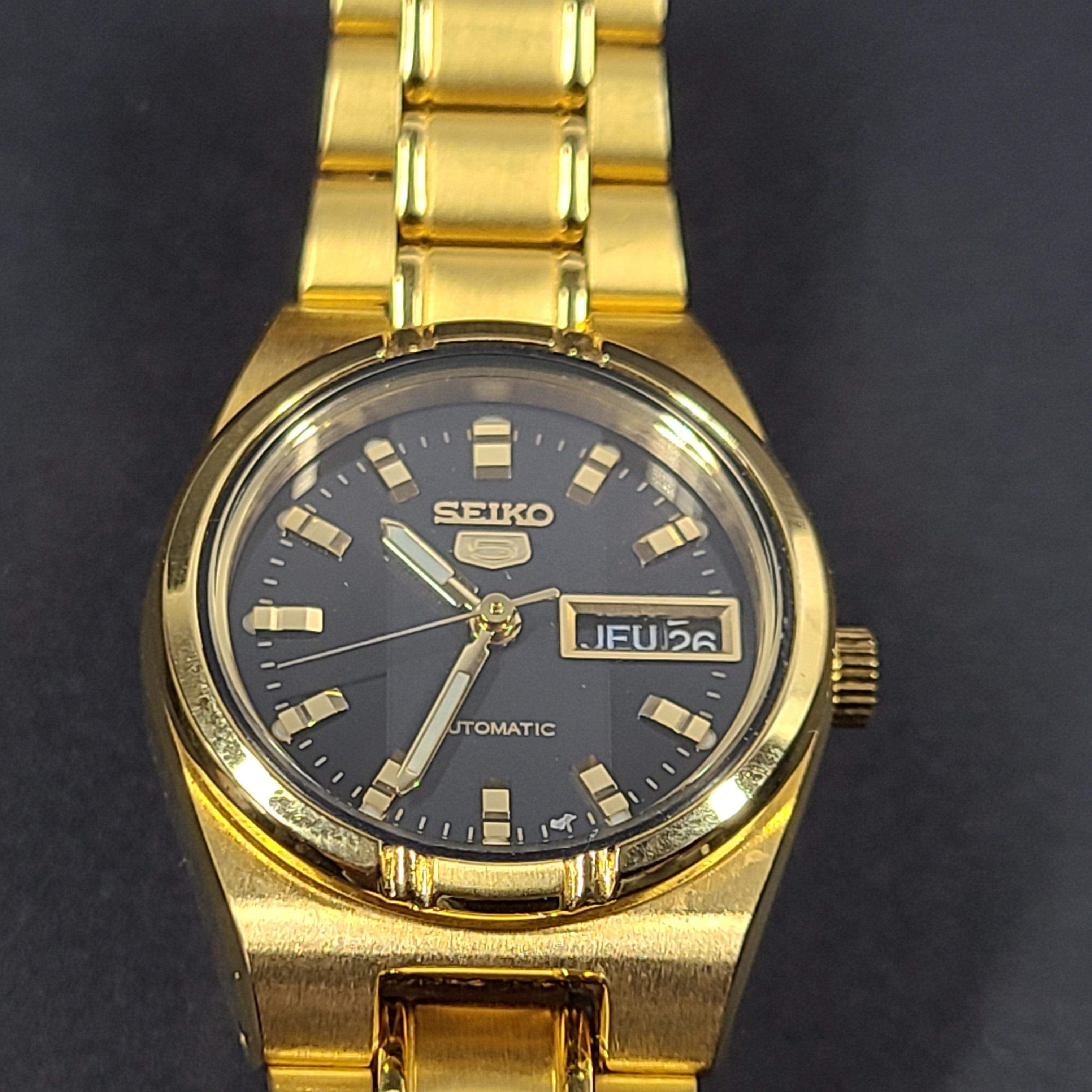 Gold-tone Seiko 5 automatic ladies watch with a black dial and stainless steel bracelet.