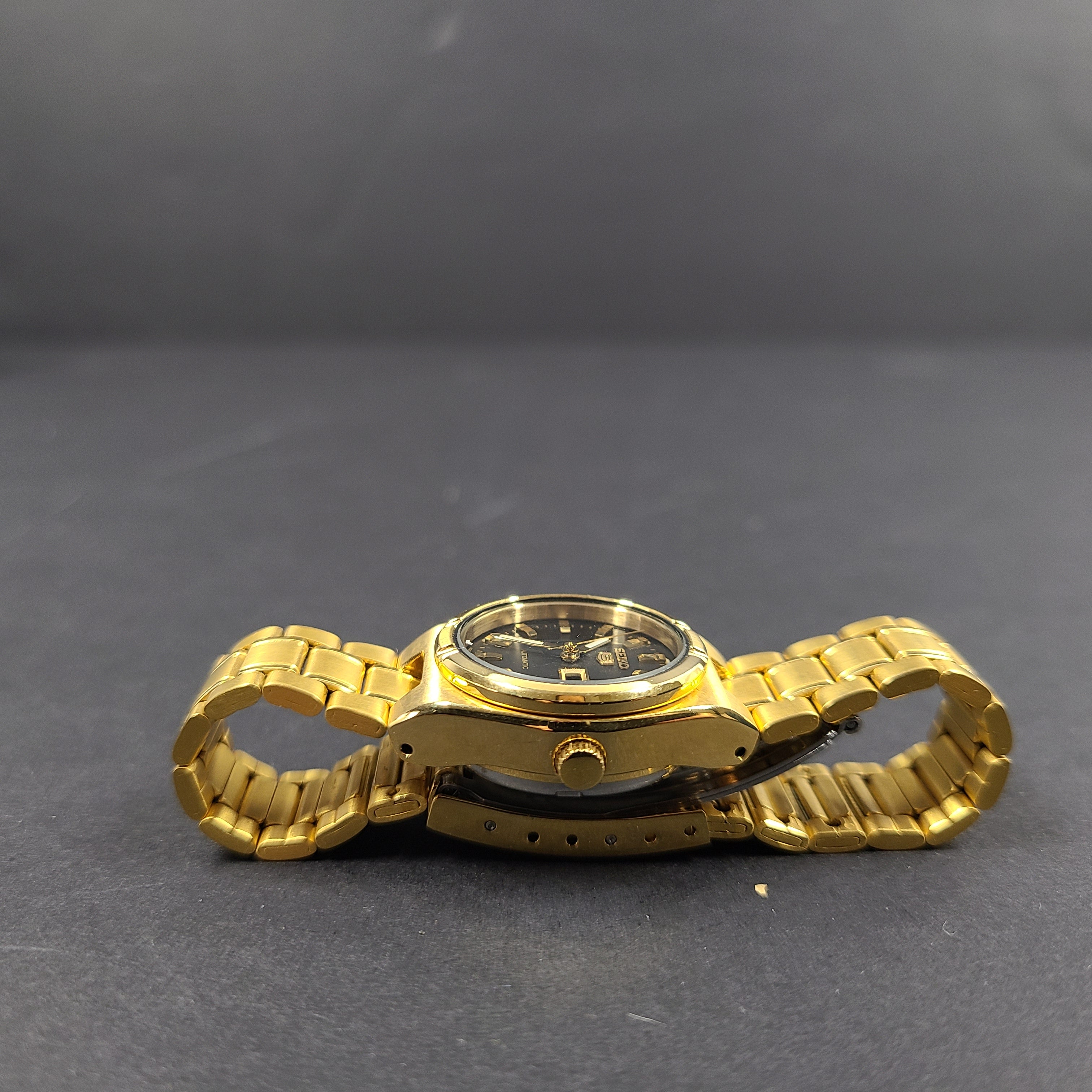 Gold-tone Seiko 5 automatic ladies watch with a black dial and stainless steel bracelet.