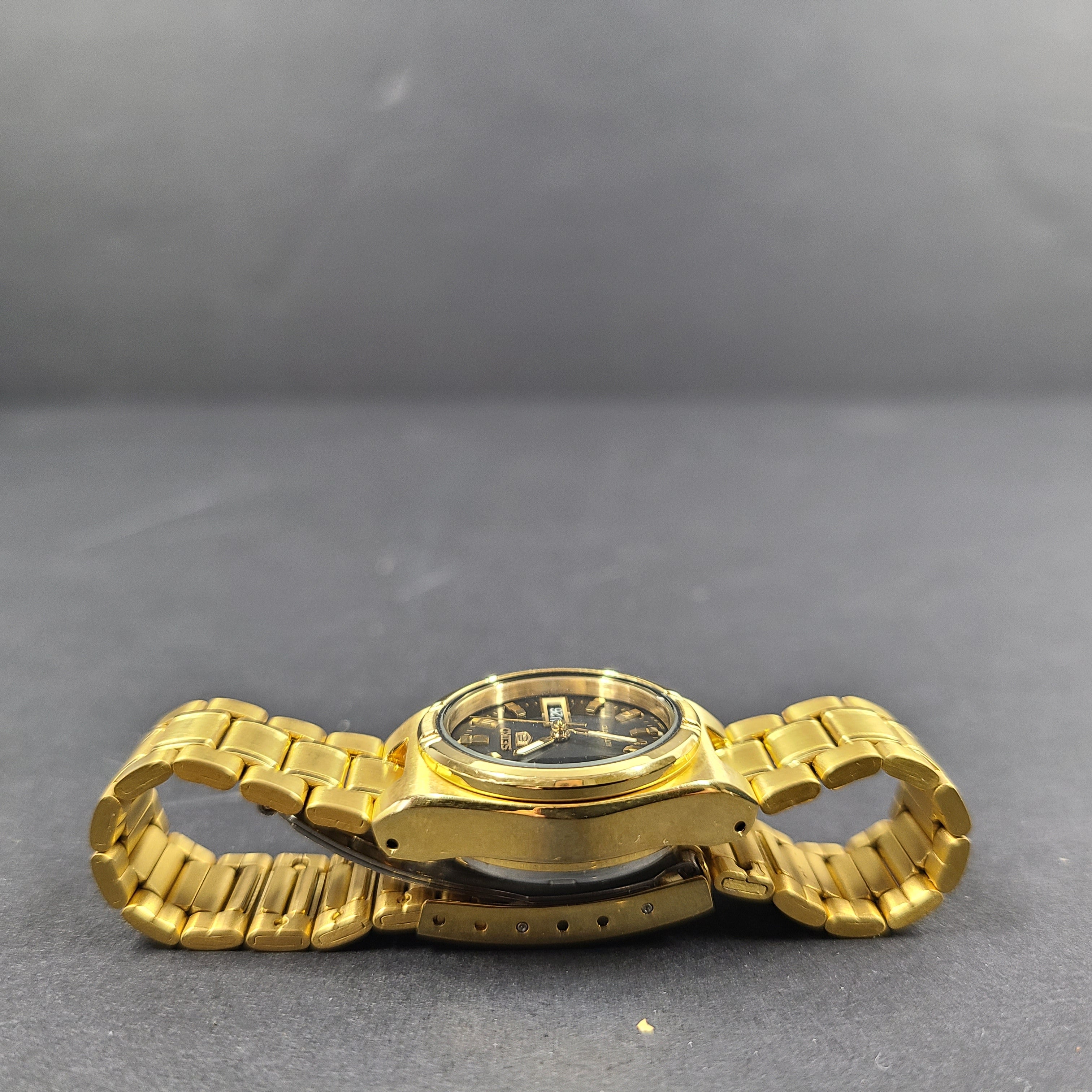 Gold-tone Seiko 5 automatic ladies watch with a black dial and stainless steel bracelet.
