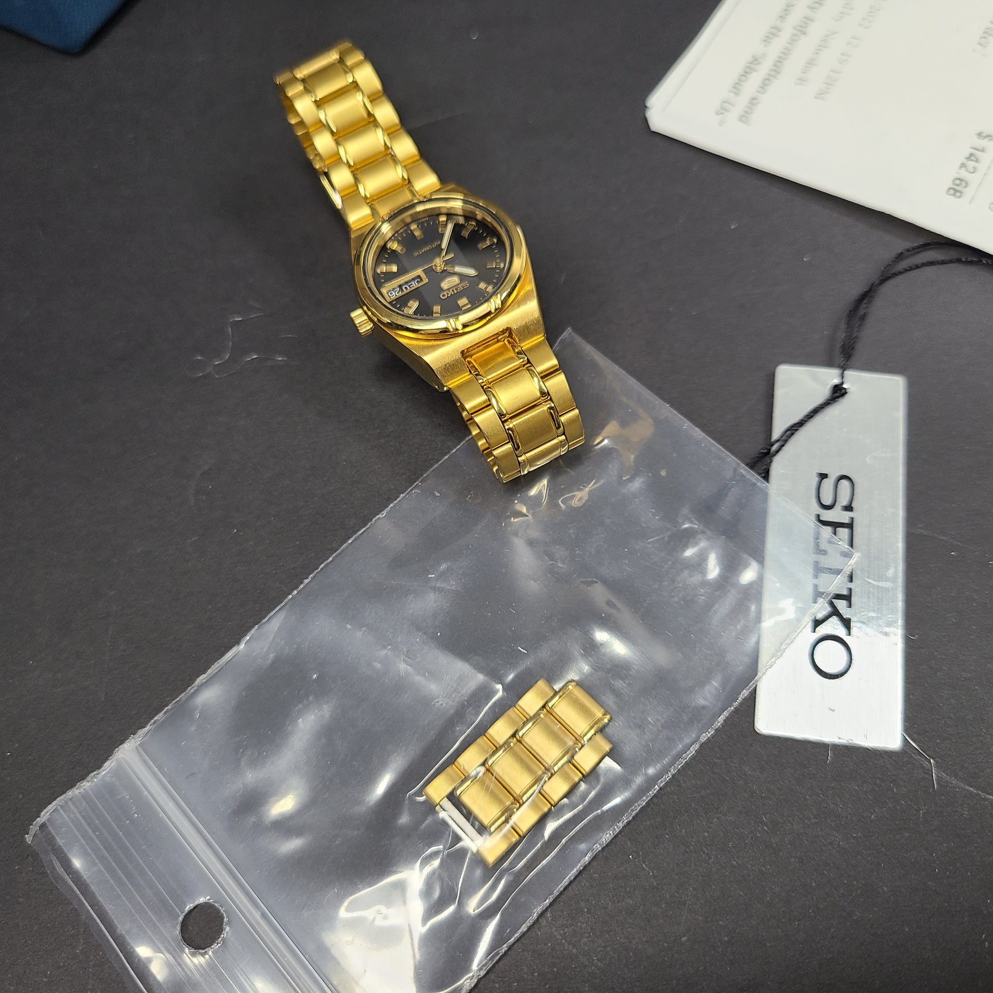 Gold-tone Seiko 5 automatic ladies watch with a black dial and stainless steel bracelet.