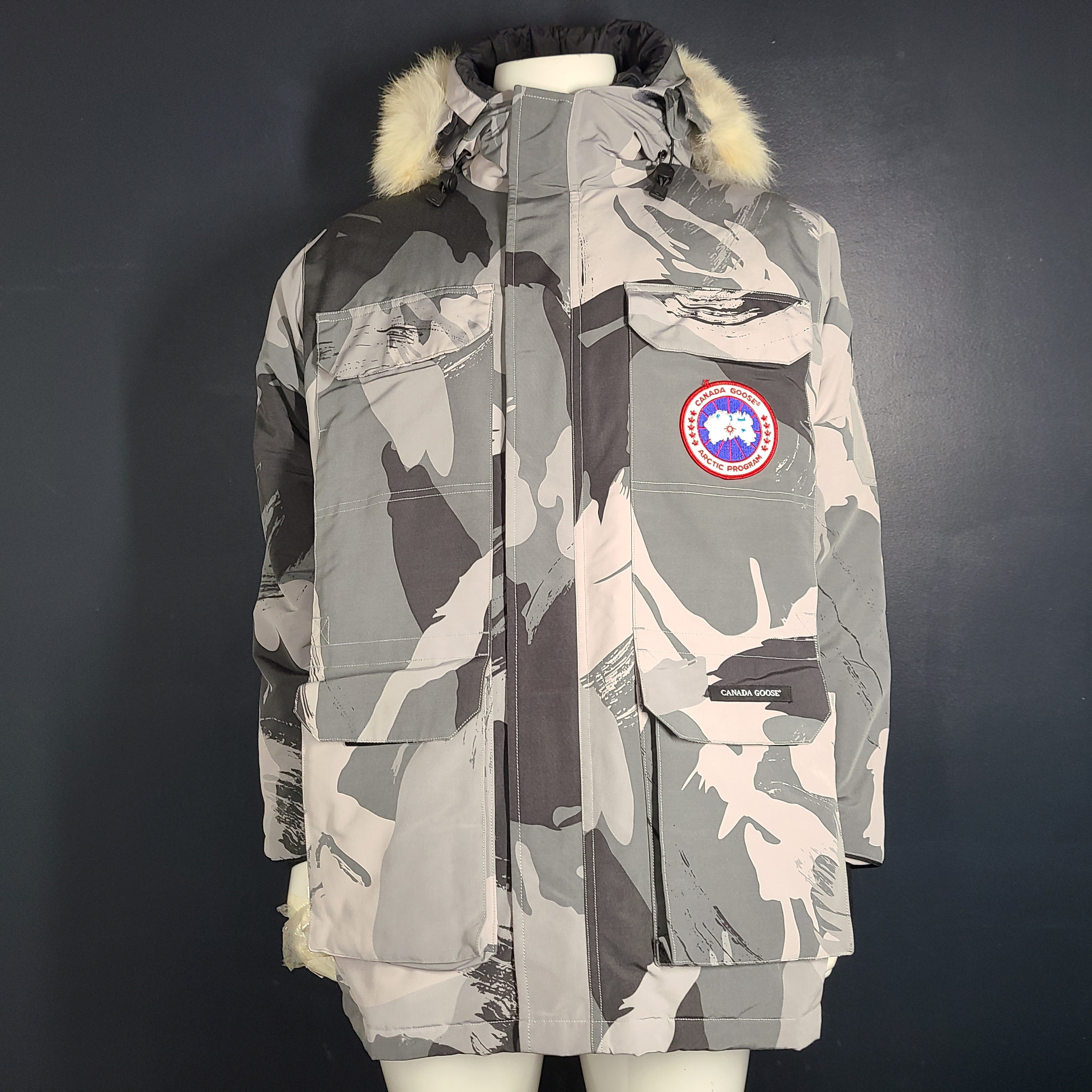 Canada Goose Expedition Parka in grey camouflage, size XL, designed for extreme cold with heavy insulation and a fur-trimmed hood.
