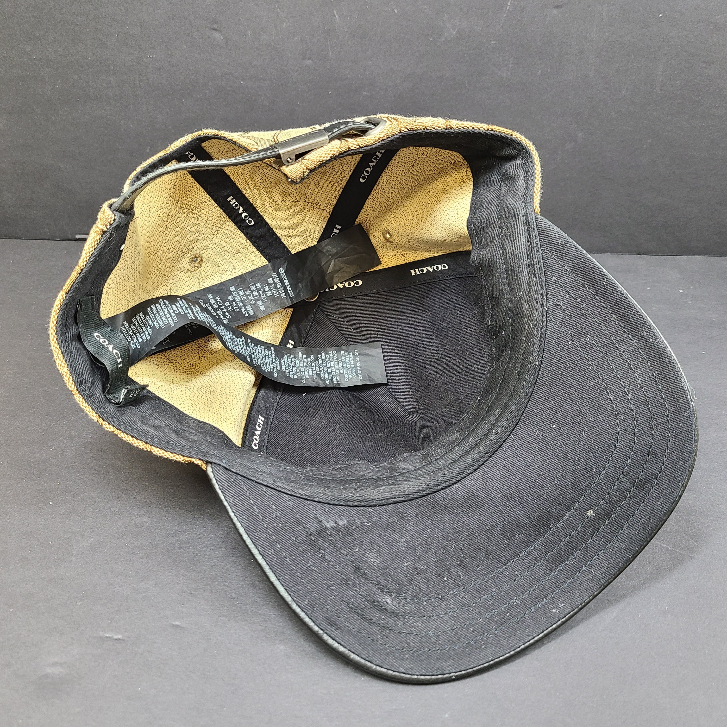 Tan and black Coach baseball cap in M/L size with canvas body and leather brim.