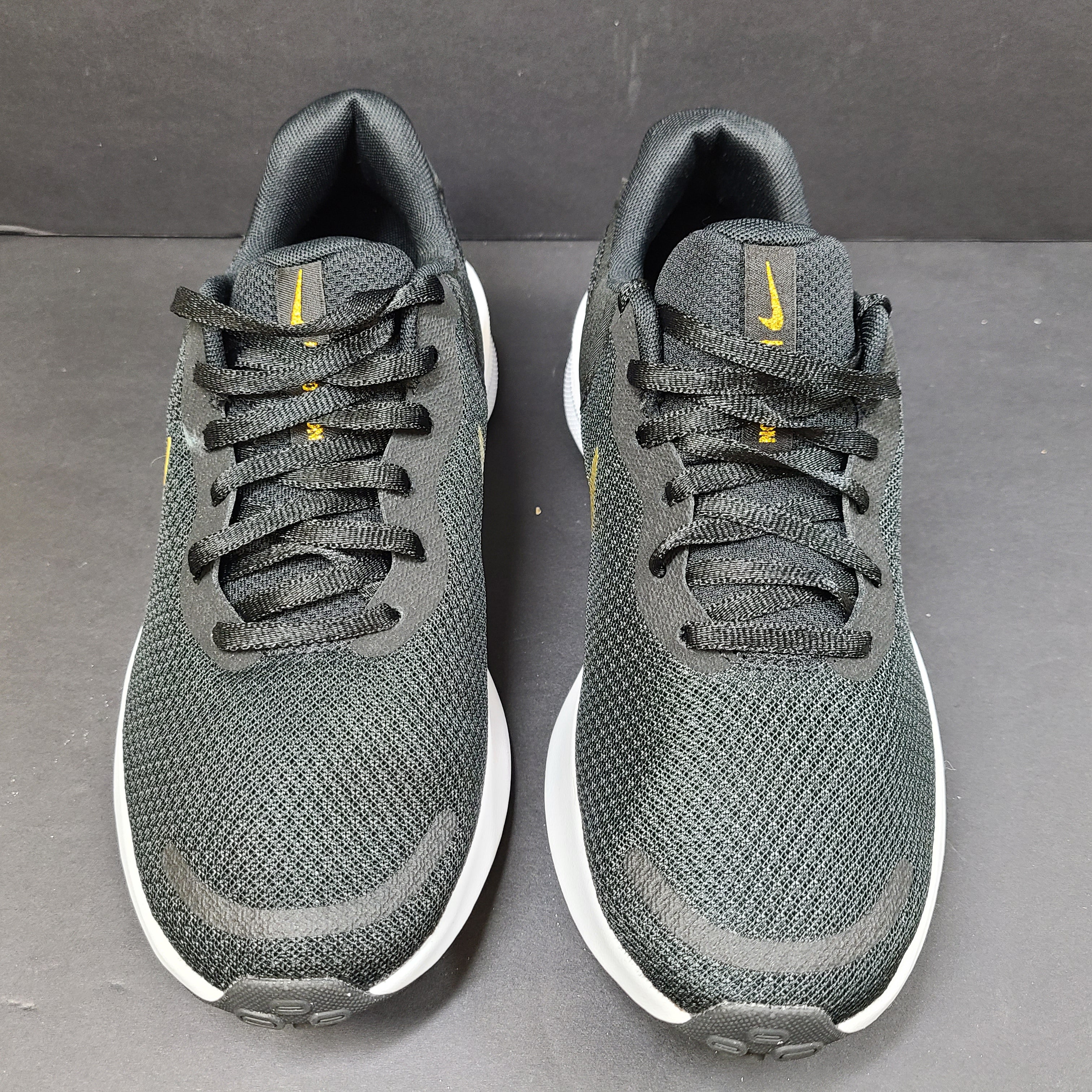 Nike Revolution 7 low-top road running shoes in black, white and metallic gold for everyday performance.