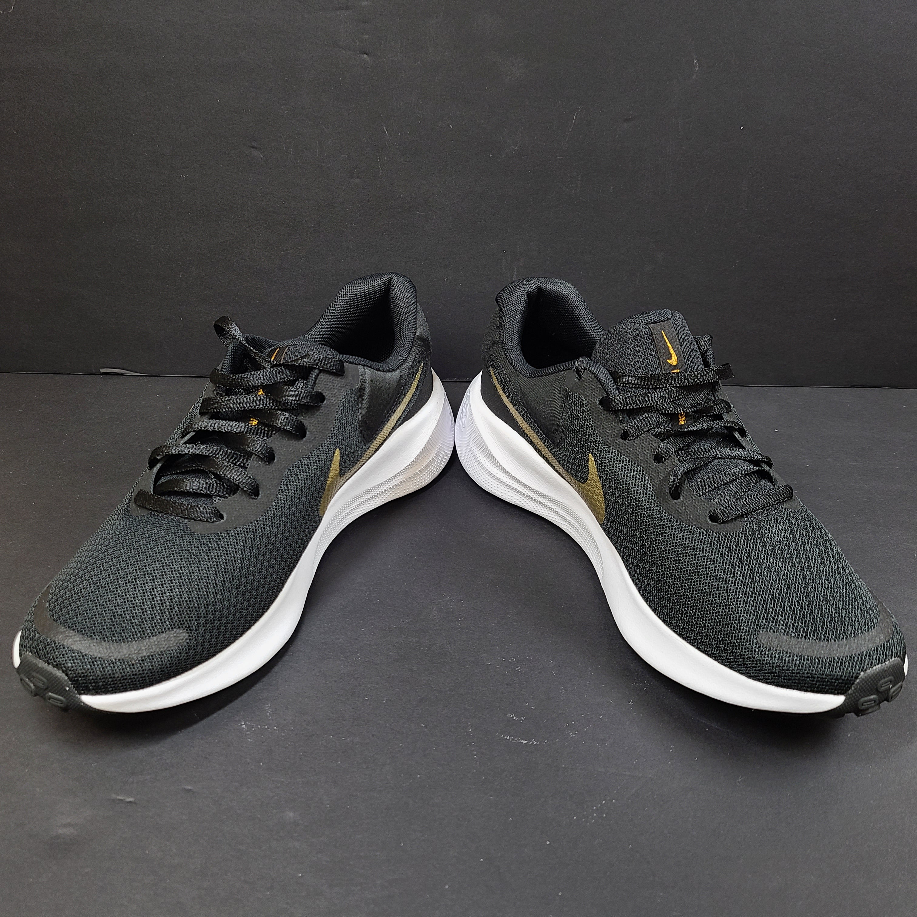 Nike Revolution 7 low-top road running shoes in black, white and metallic gold for everyday performance.