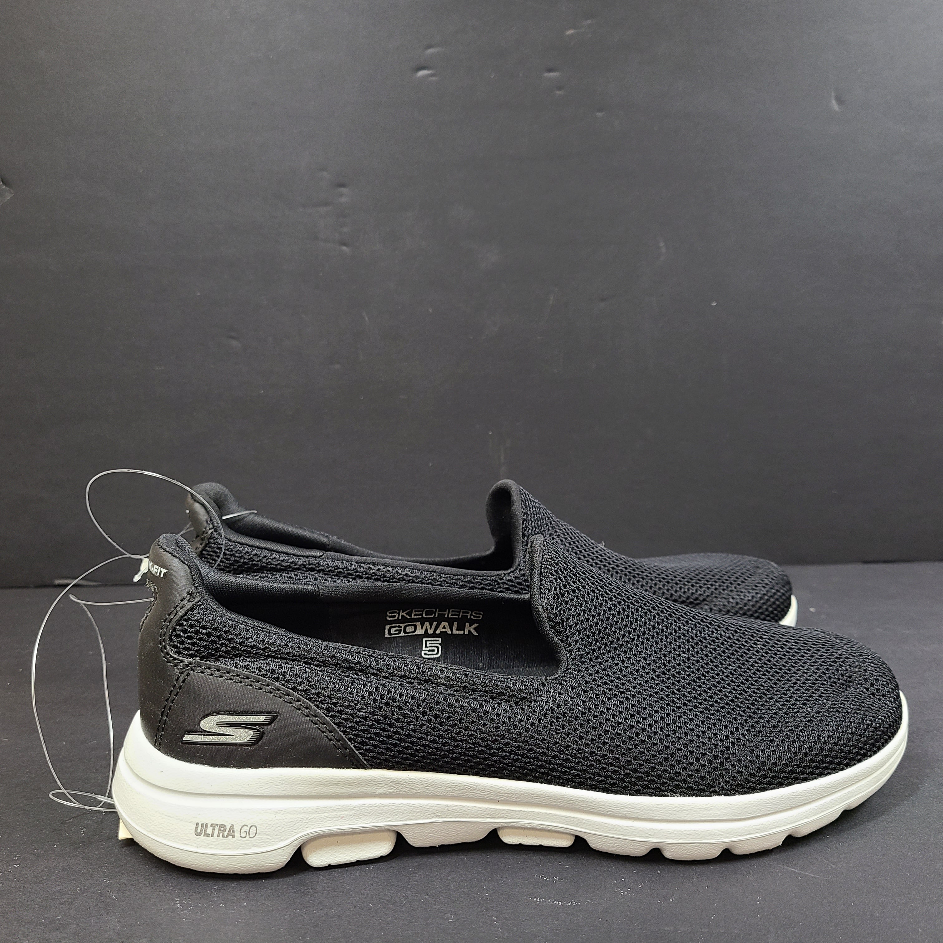 Black and white Skechers Go Walk 5 slip-on shoes with responsive cushioning and Quick-Fit heel for easy on and off.