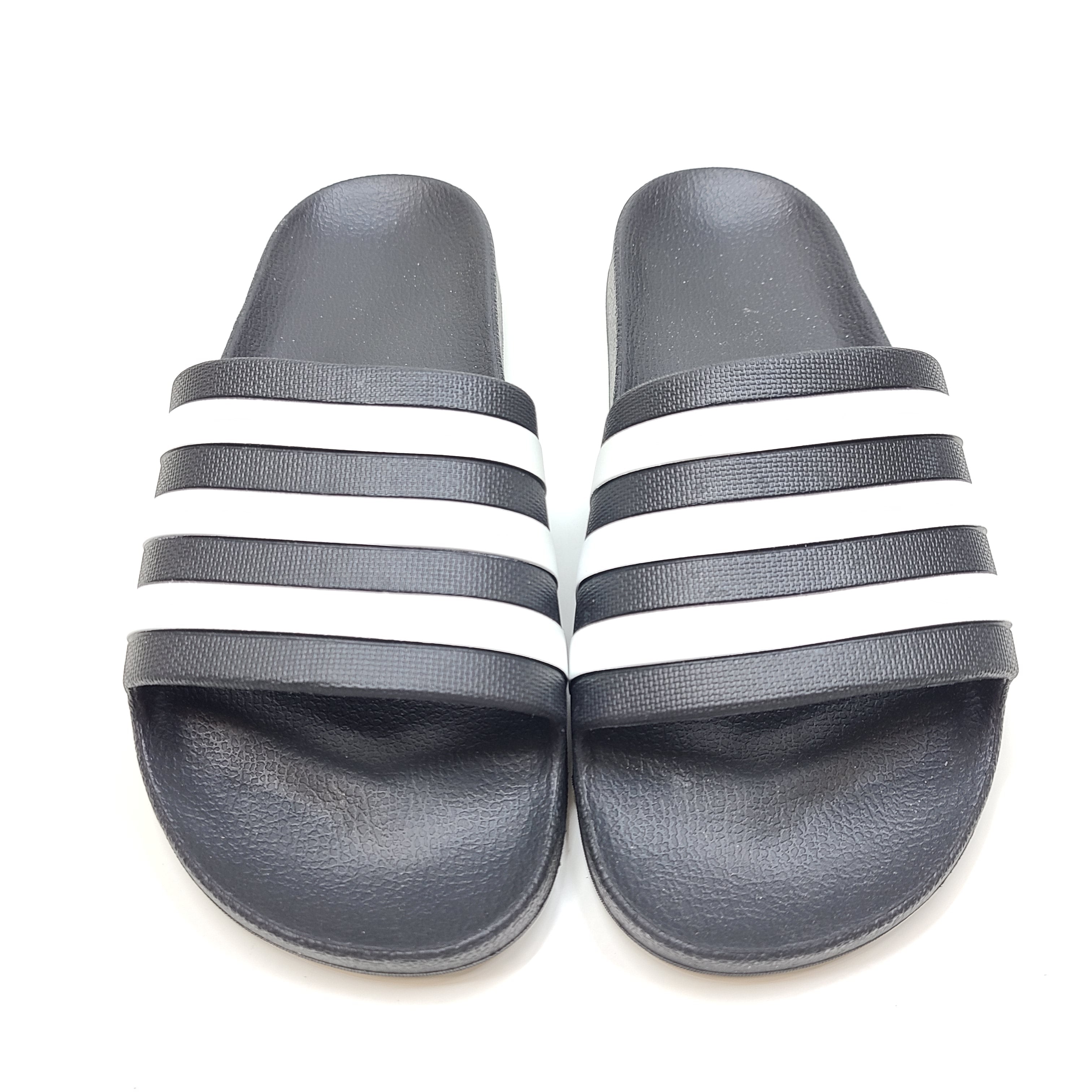 A black Adidas Adilette slide with white three-stripes and a cushioned footbed in UK size 7 (US M 8).
