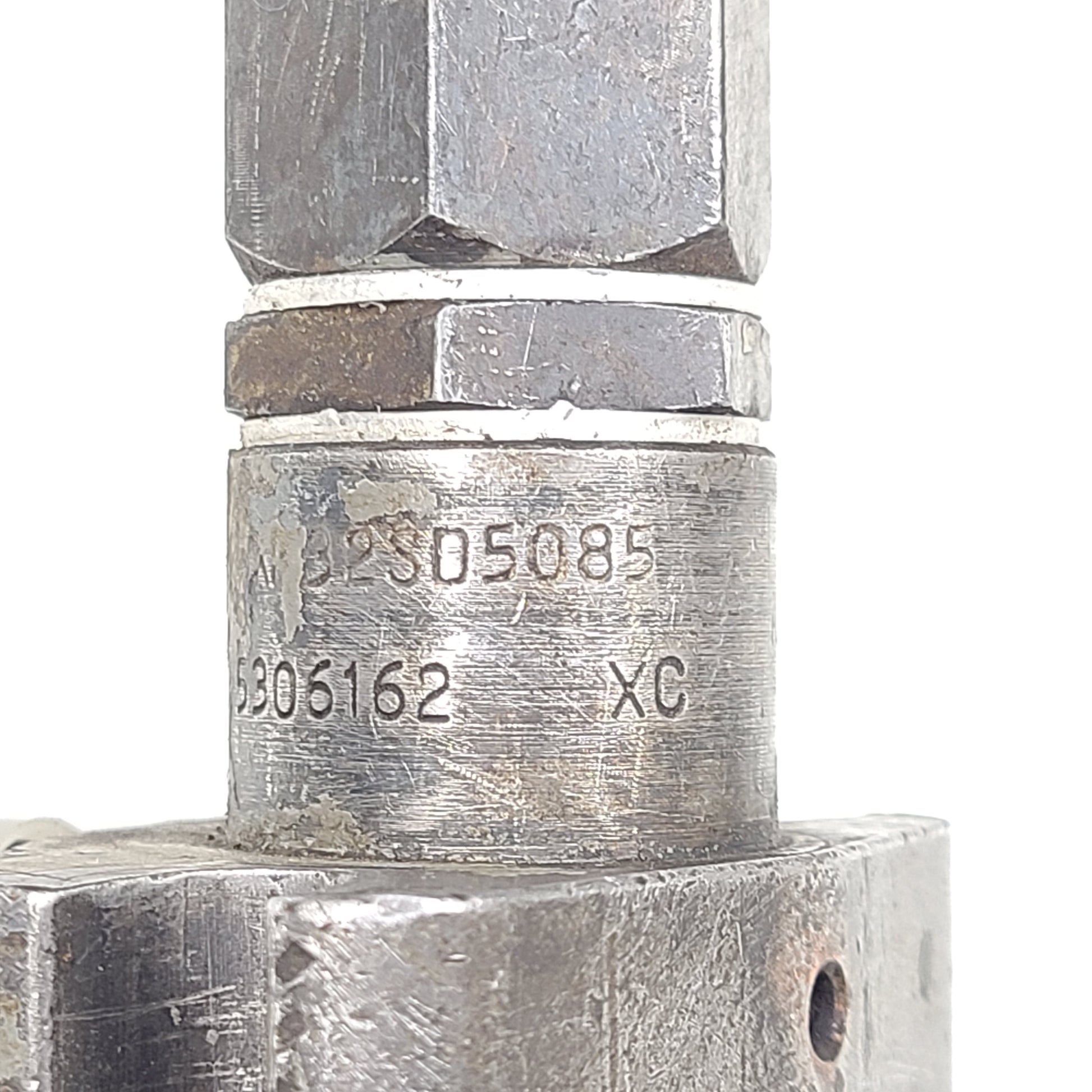 Silver hydraulic valve A3205085 with part marking 5306162 XC and surface wear.