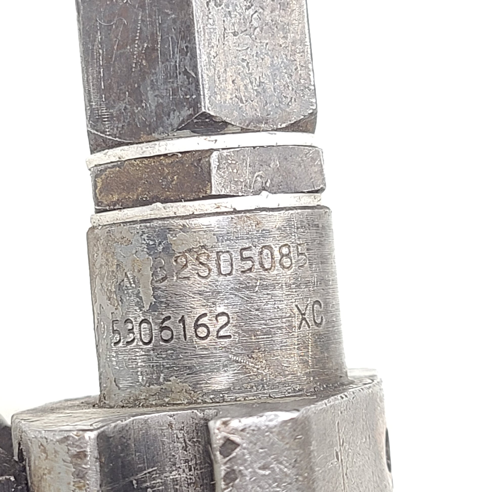 Silver hydraulic valve A3205085 with part marking 5306162 XC and surface wear.