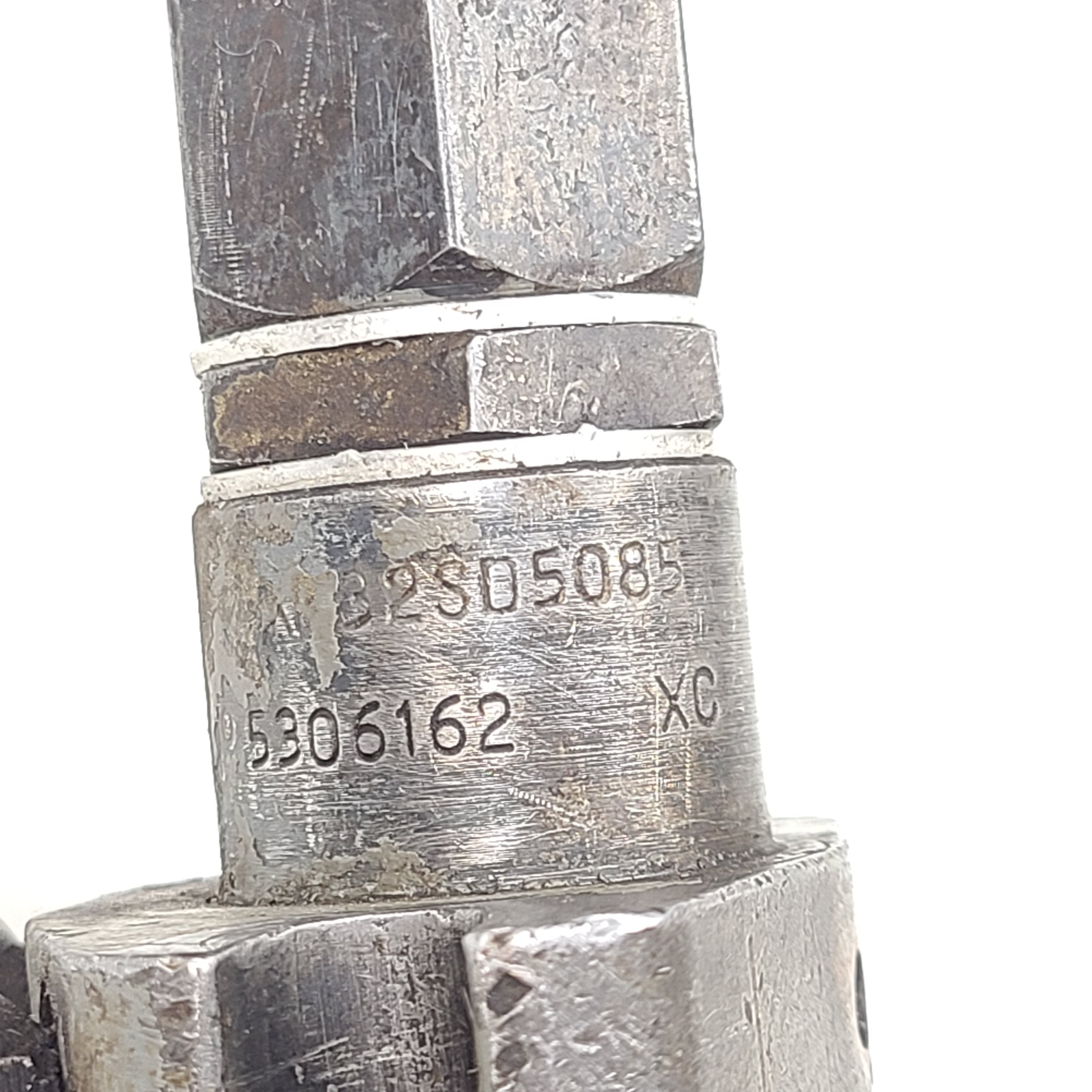 Silver hydraulic valve A3205085 with part marking 5306162 XC and surface wear.