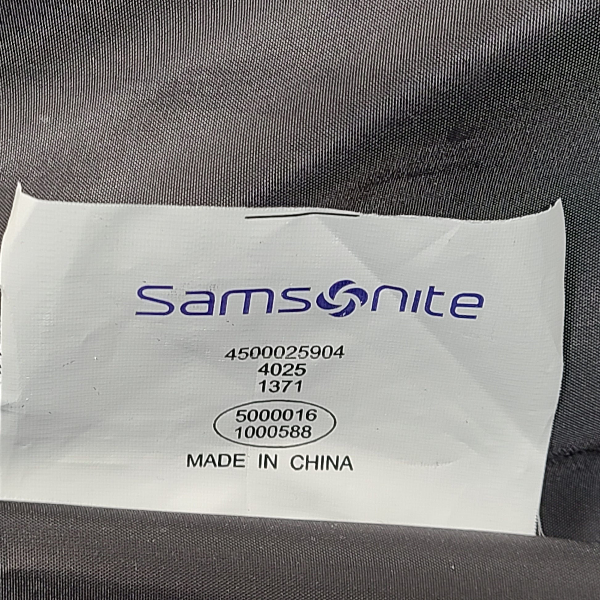 Green Samsonite suitcase model 4500025904 with scuff marks on wheels and handles.